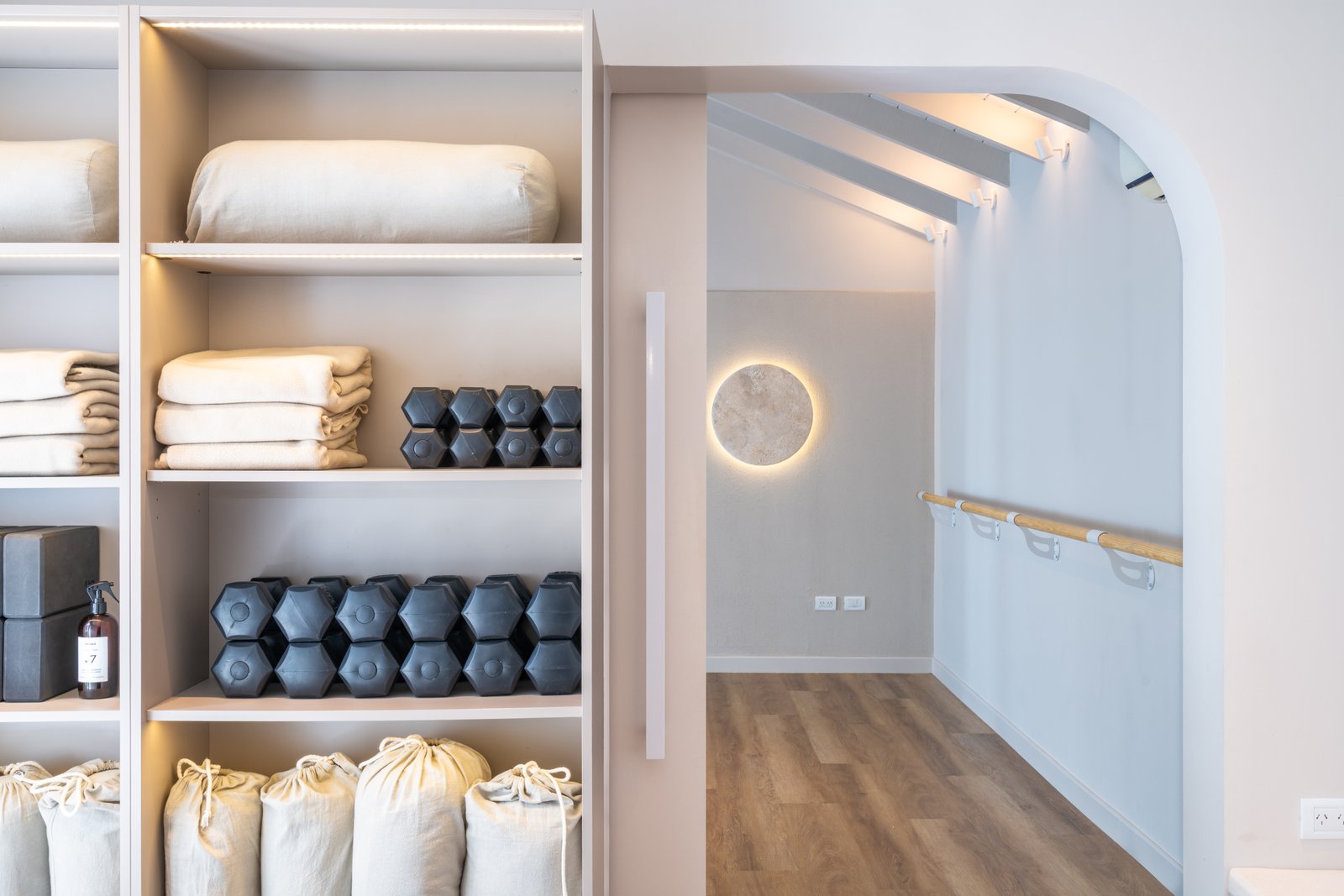 Estanterías blancas integradas, arco y ambiente de estudio de yoga — proyecto ALMA MATTER, por Maria Menna Arquitecta, en Mar del Plata