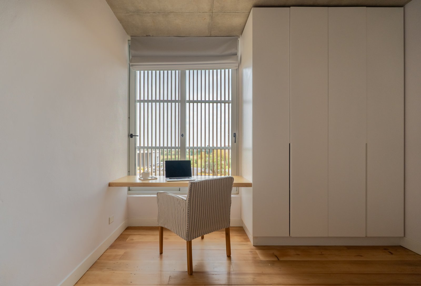 Oficina minimalista con escritorio flotante y silla a rayas — proyecto Carpinchos, por LACROZE DESIGN STUDIO, en Nordelta