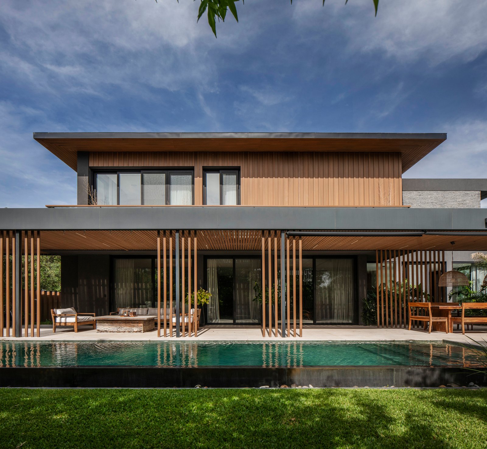 Fachada moderna de casa com madeira, pergolado e piscina — projeto Obra Kahala, por lifecycle, em City Bell