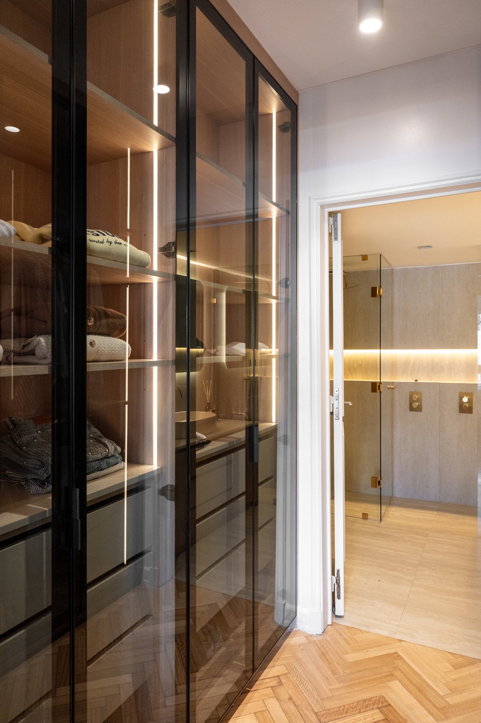 Vestidor moderno con puertas de vidrio e iluminación integrada — proyecto ALVEAR TYM, por AB ARQUITECTURA, en Recoleta