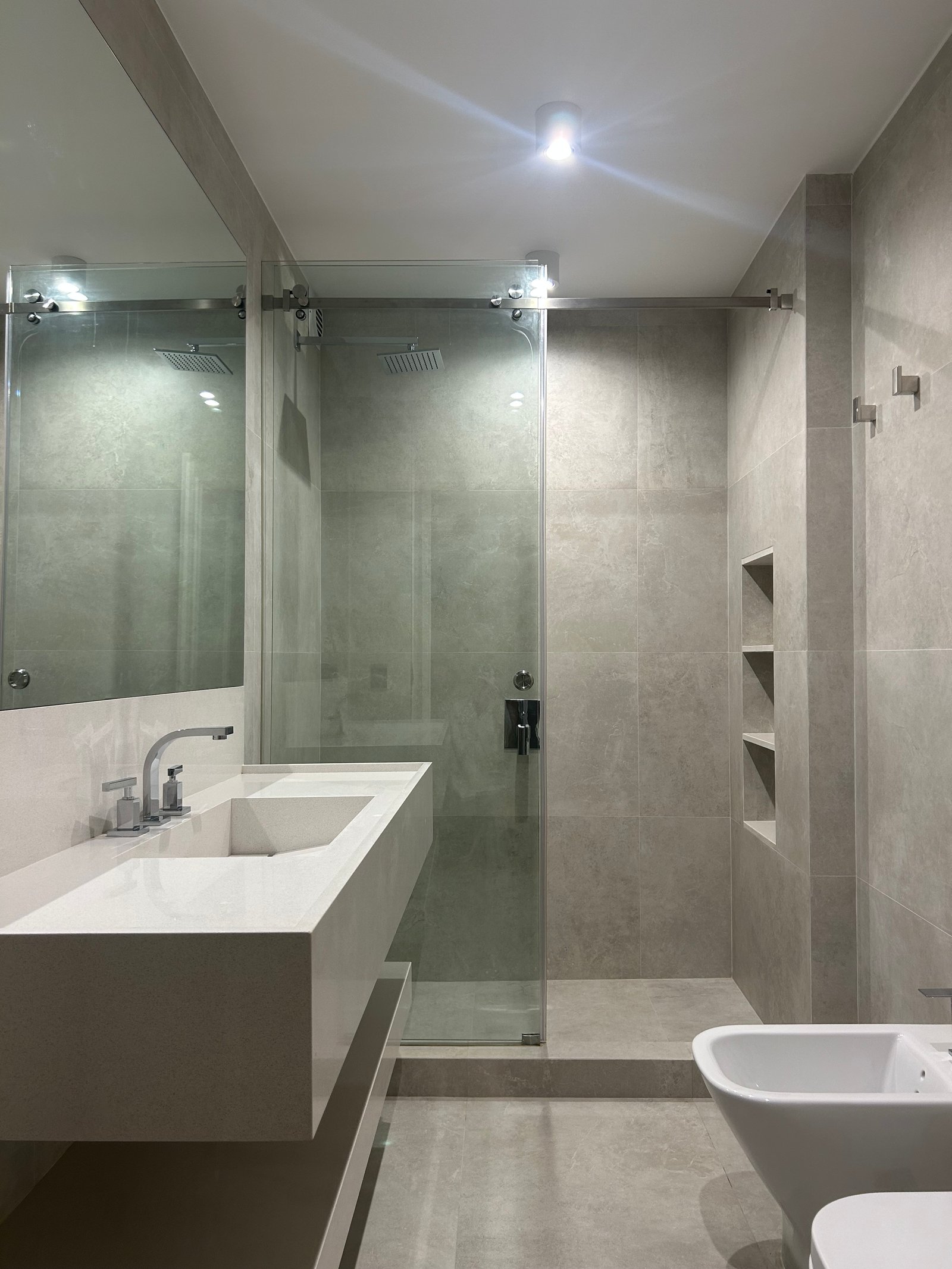 Baño moderno con revestimiento de piedra gris y bidet — proyecto QUINTANA, por ESTUDIO TEZ, en Recoleta