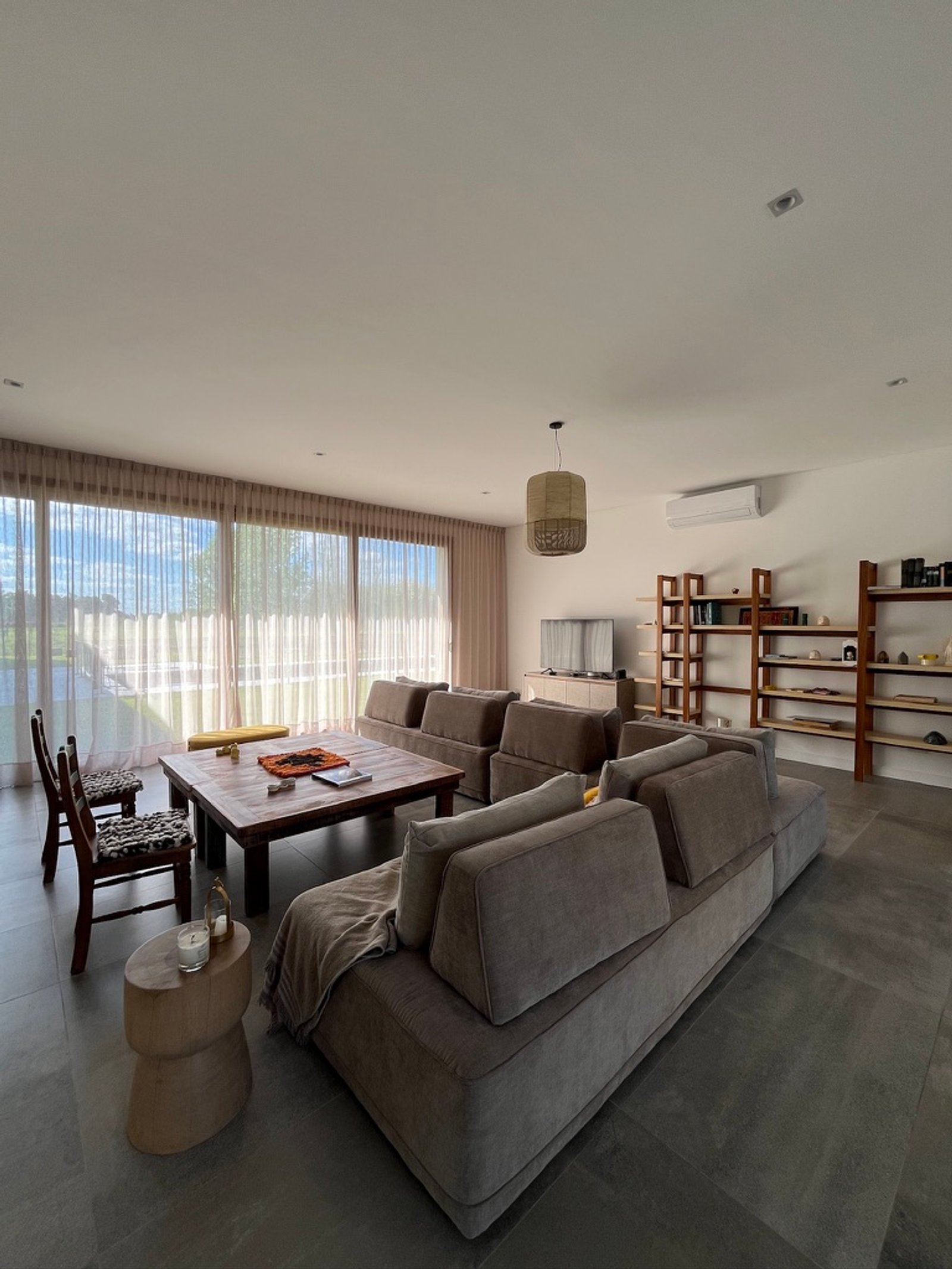 Living moderno con sofá modular y grandes ventanales — proyecto La Colina, por Arcucci Arquitectura, en La Colina Villa de Campo