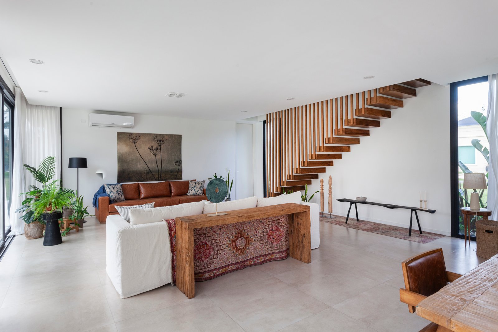 Sala de estar moderna estilo boho com escada flutuante e muita luz — projeto CASA HS143, por A'PRIMA - Arquitectura Sustentable, em km 7.5 Ruta 25