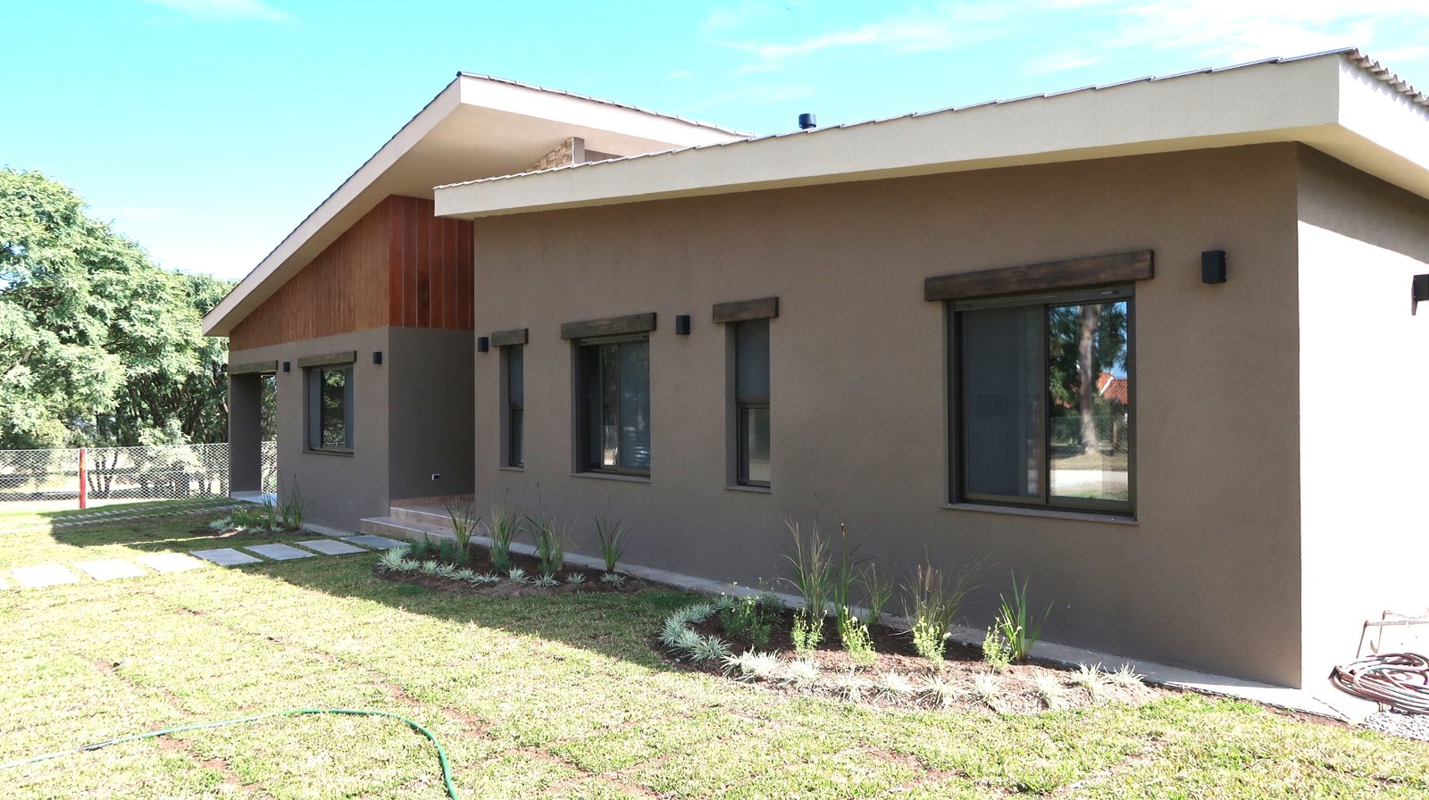 Fachada moderna de casa residencial con detalles en madera — proyecto Casa La Paz, por Luciana González Anderson, en Salta