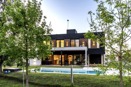Fachada moderna con piscina, amplios ventanales y vegetación — proyecto Casa ALM57, por EZ architects, en Canning