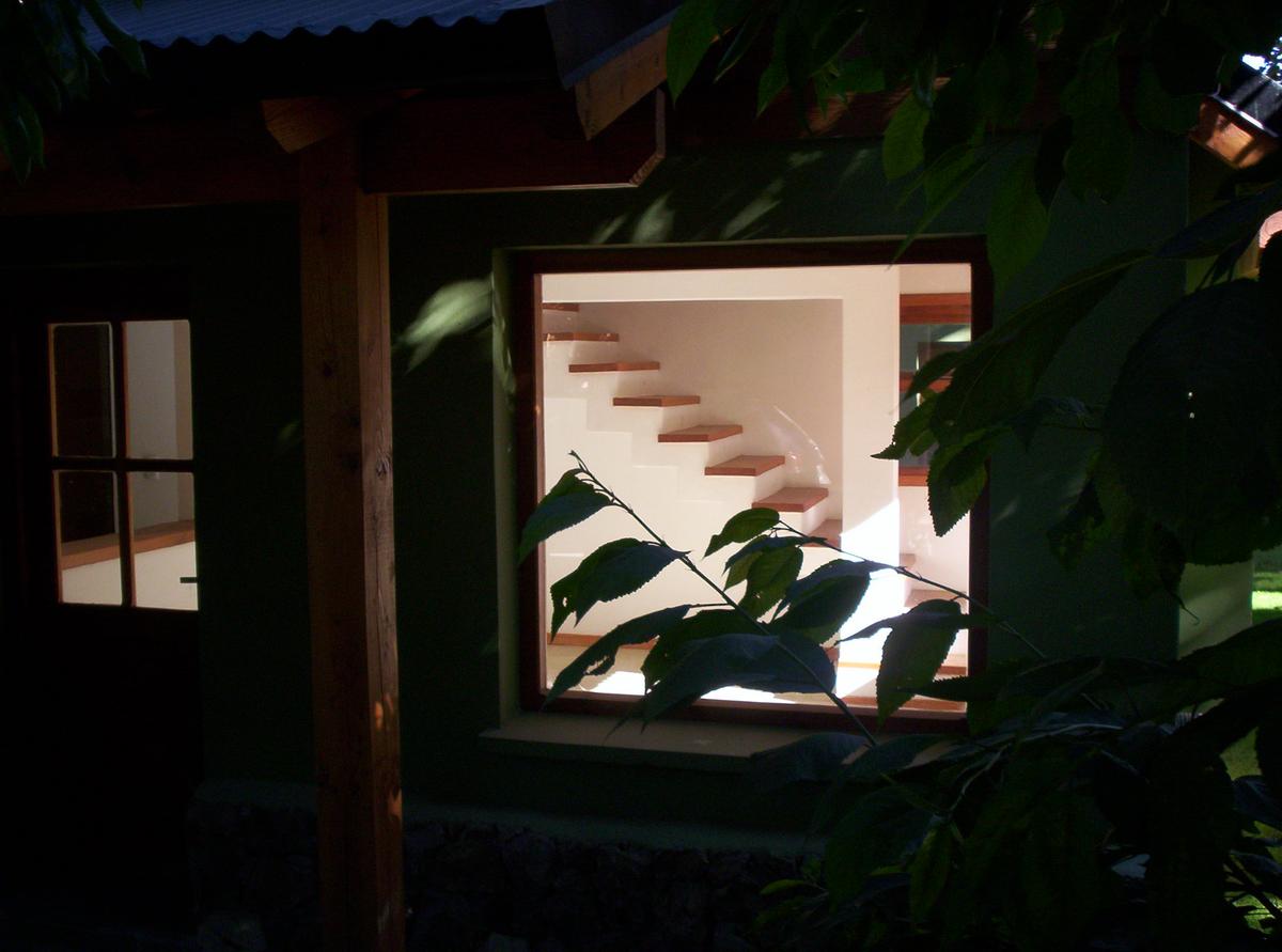 Fachada moderna com vegetação exuberante e escada flutuante à noite — projeto Complejo de Cabañas, por ESTUDIO ARQ.GABRIEL ARIAS, em San Carlos de Bariloche