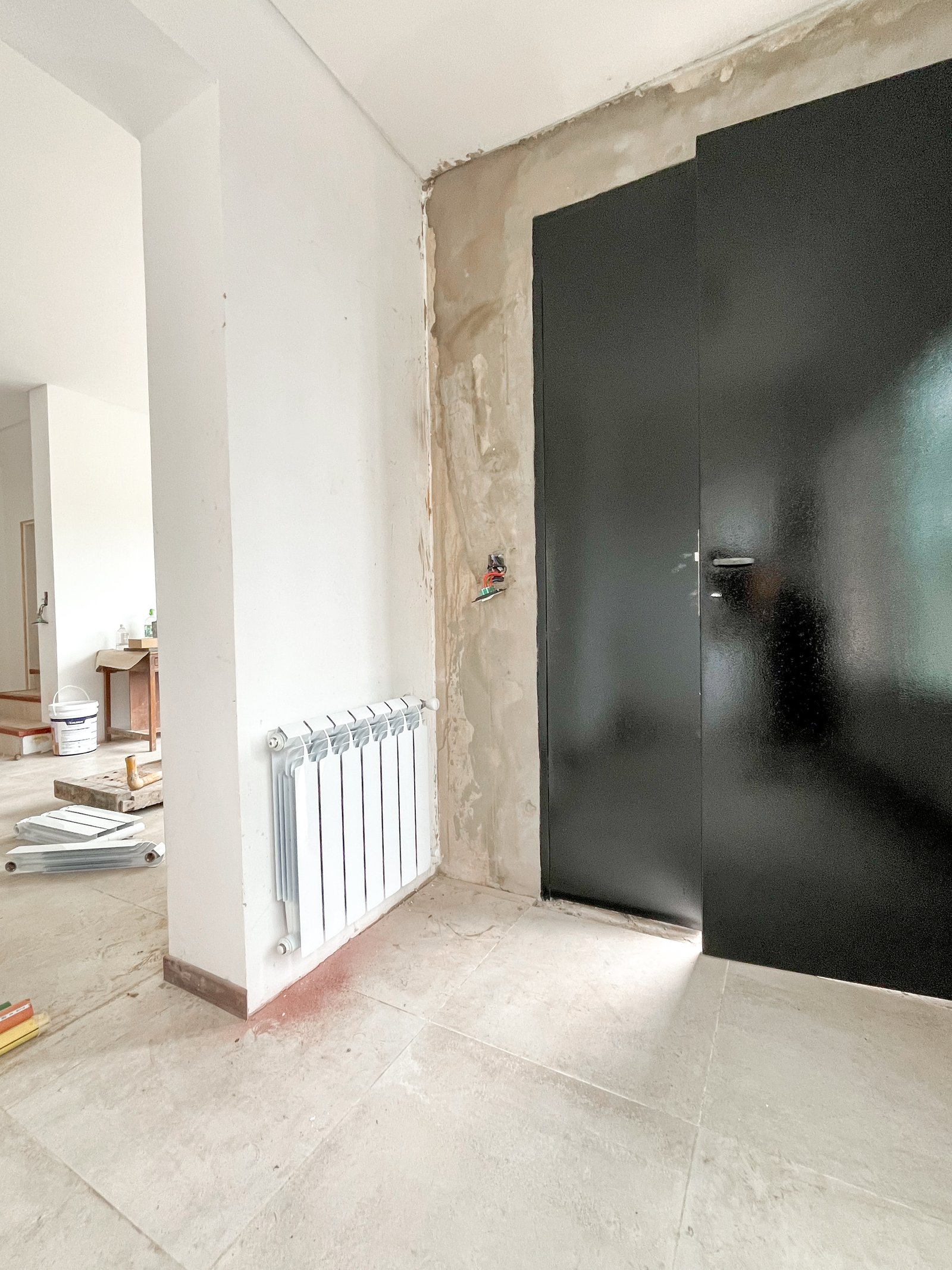 Hall de obra con puerta negra y radiador blanco — proyecto Instalación de Radiadores en Tigre, por Climatizacion HD, en B1648 Tigre