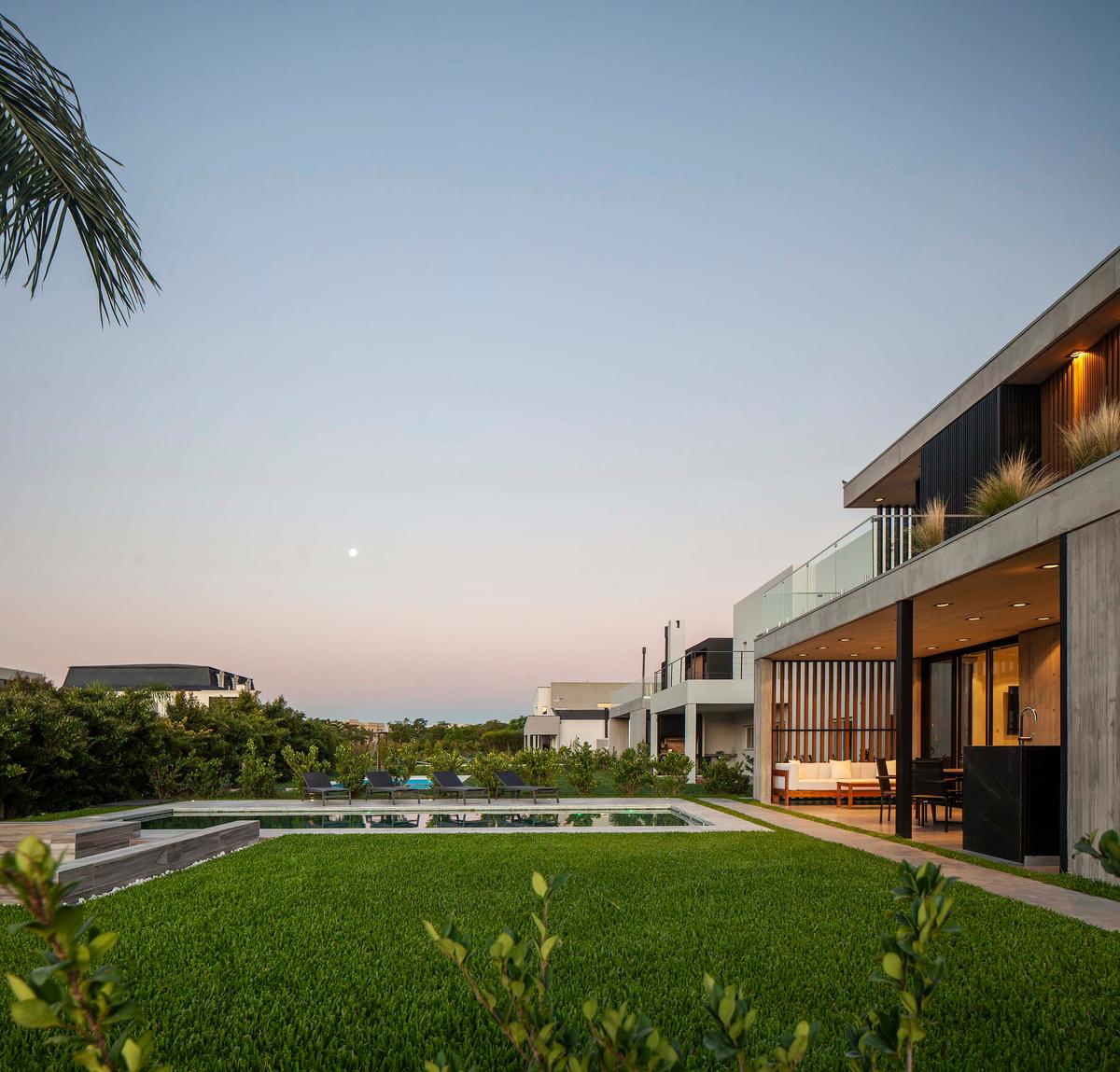 Fachada moderna com piscina e deck de madeira em área costeira — projeto DISEÑO INTERIOR - CASA VISTAS, por FOCO_arquitectura&diseñointerior, em Belén de Escobar