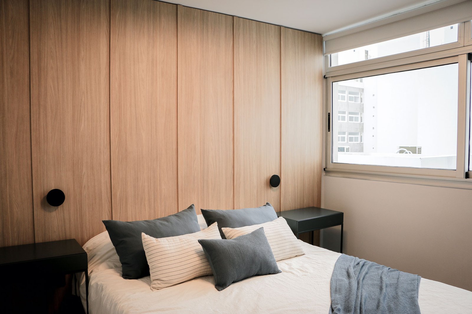 Quarto moderno com painéis de madeira e iluminação indireta — projeto Departamento Airbnb, por Jeitinho Estudió Creativo, em La Plata