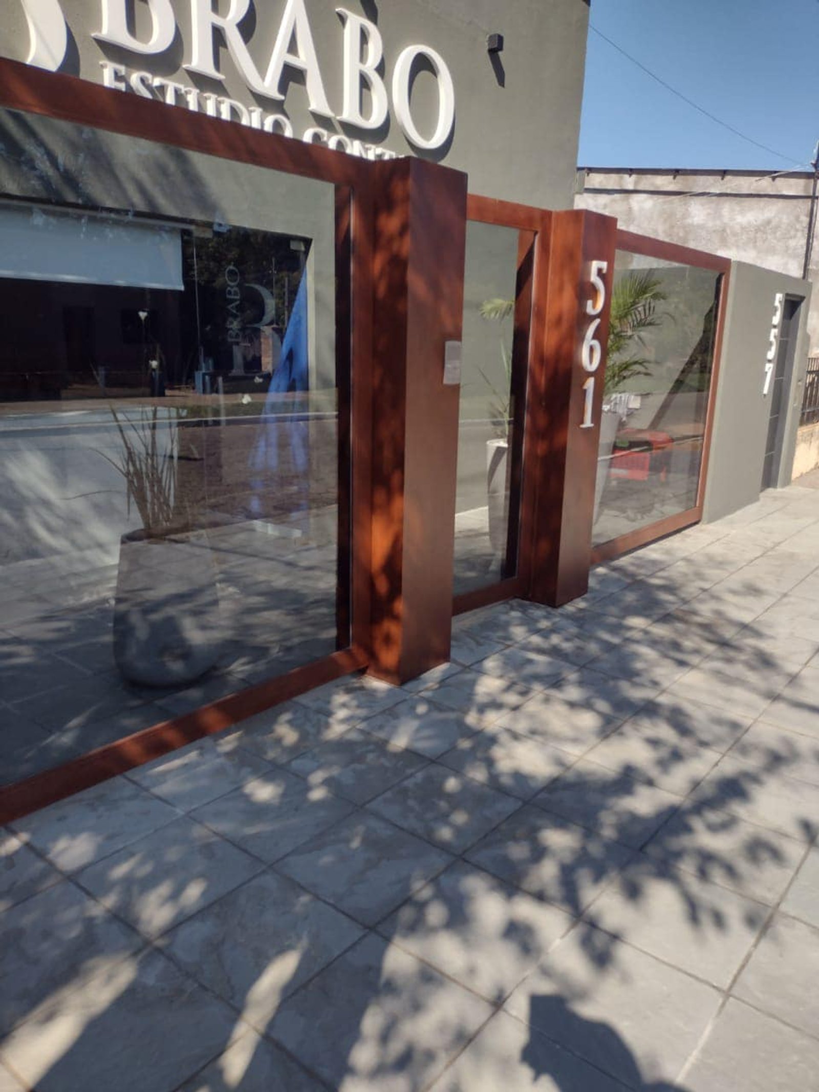 Fachada moderna com janelas do chão ao teto e detalhes em madeira escura — projeto Esudio Contable, por Arquitecto Gustavo Maidana, em Caá Catí