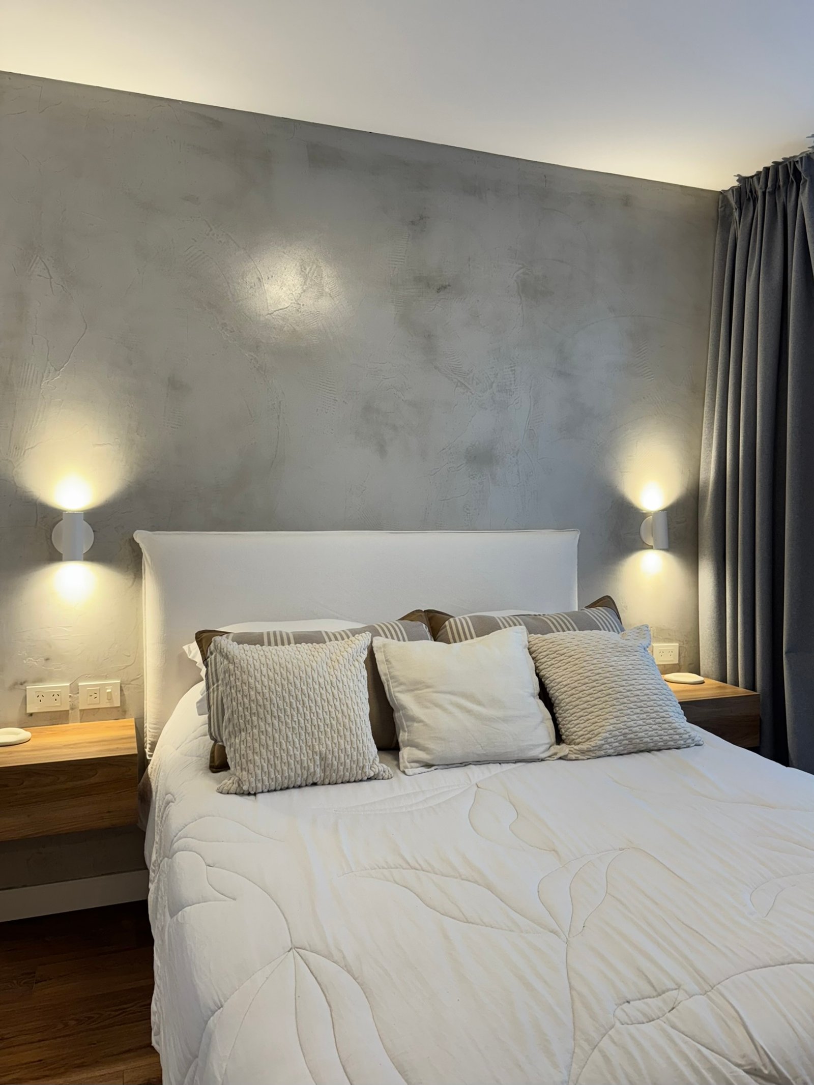 Dormitorio moderno con paredes de microcemento gris y cama blanca — proyecto Ciudad de la Paz, por MDBK Arquitectura, en Belgrano