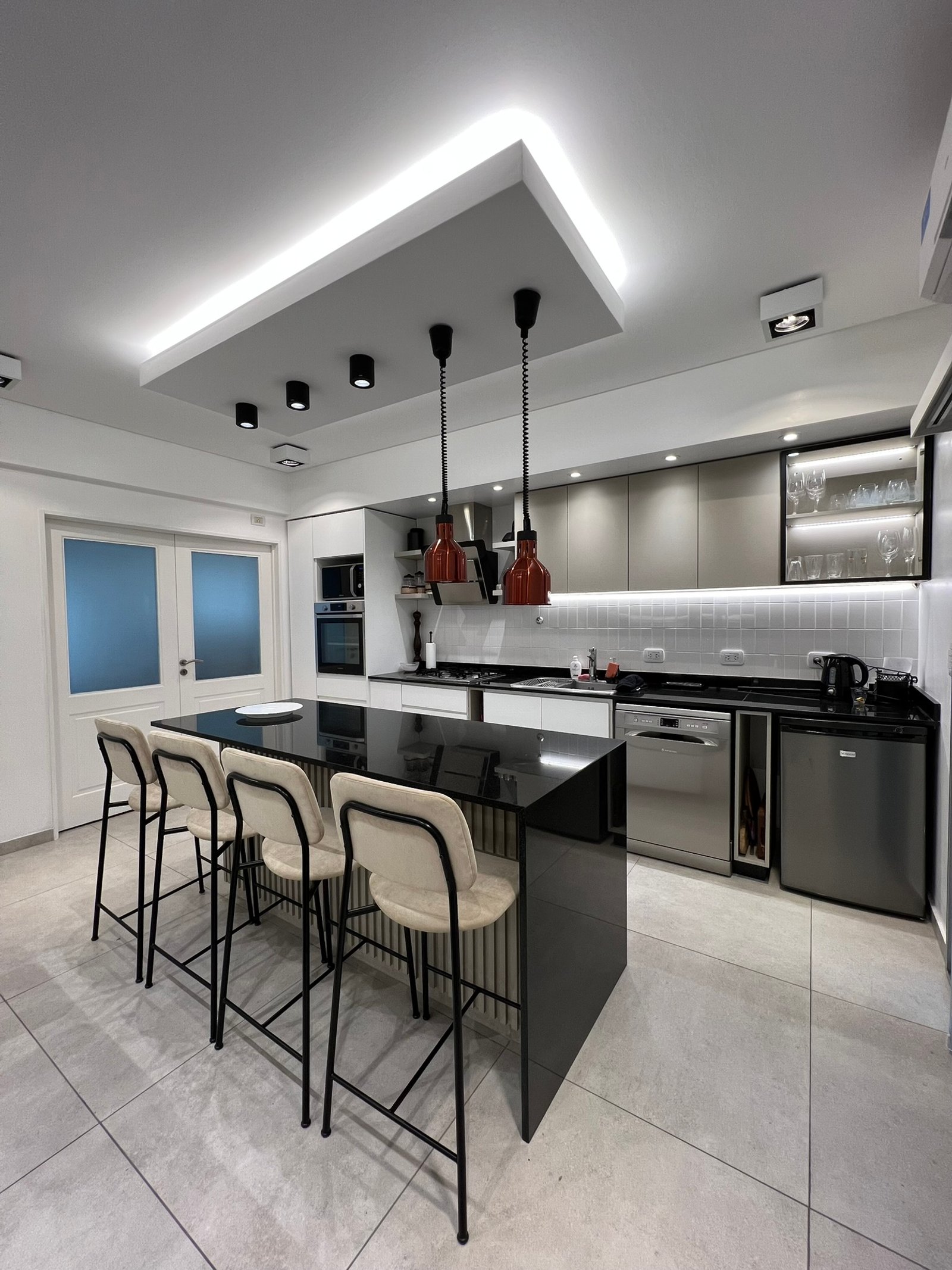 Cocina moderna con isla y barra, luces indirectas, isla de cascada — proyecto Victor Martinez, por MDBK Arquitectura, en Villa Crespo