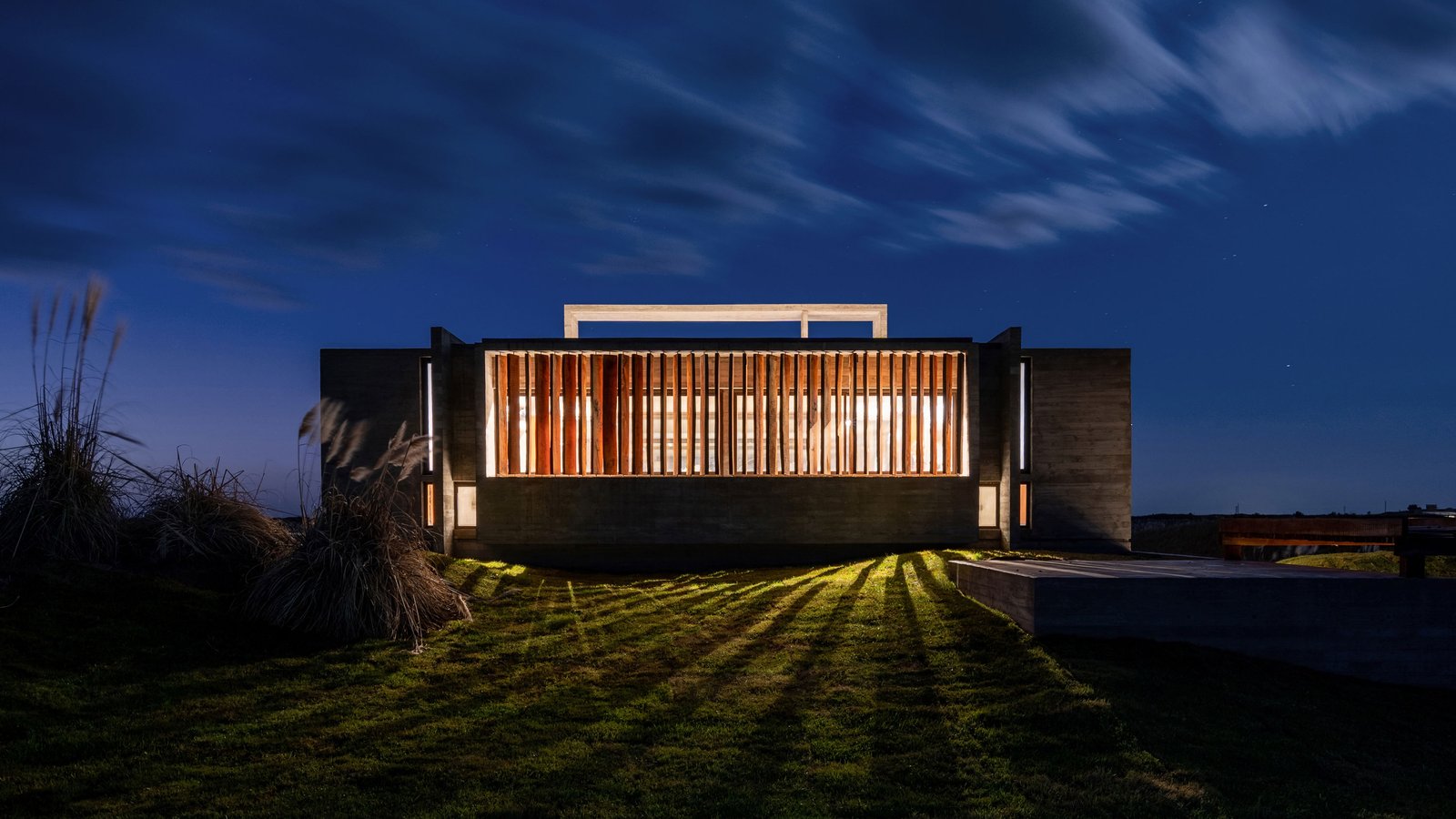 Casa moderna de concreto con pantalla de madera en la costa — proyecto Casa Médanos, por Besonías Almeida arquitectos, en JWRC+MQ