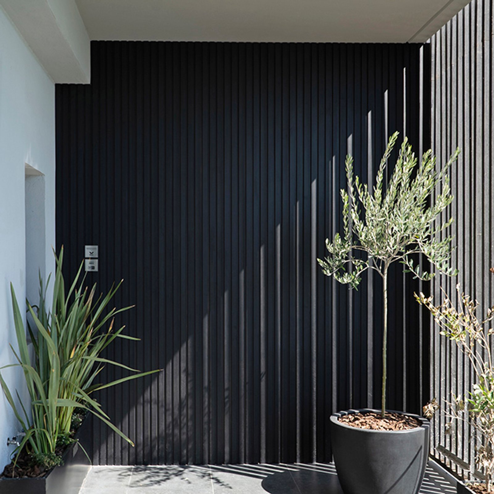 Fachada moderna con revestimiento de madera y pantallas metálicas — proyecto Revestimiento de Aluminio, por Aluar División Elaborados