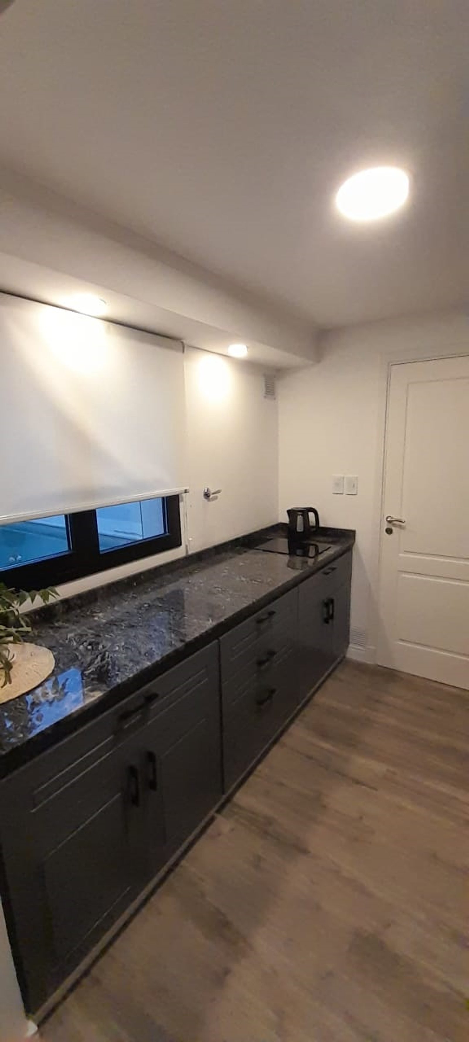 Cozinha moderna com armários cinza e bancadas de pedra preta — projeto Casa FF, por Forma, em Balcarce