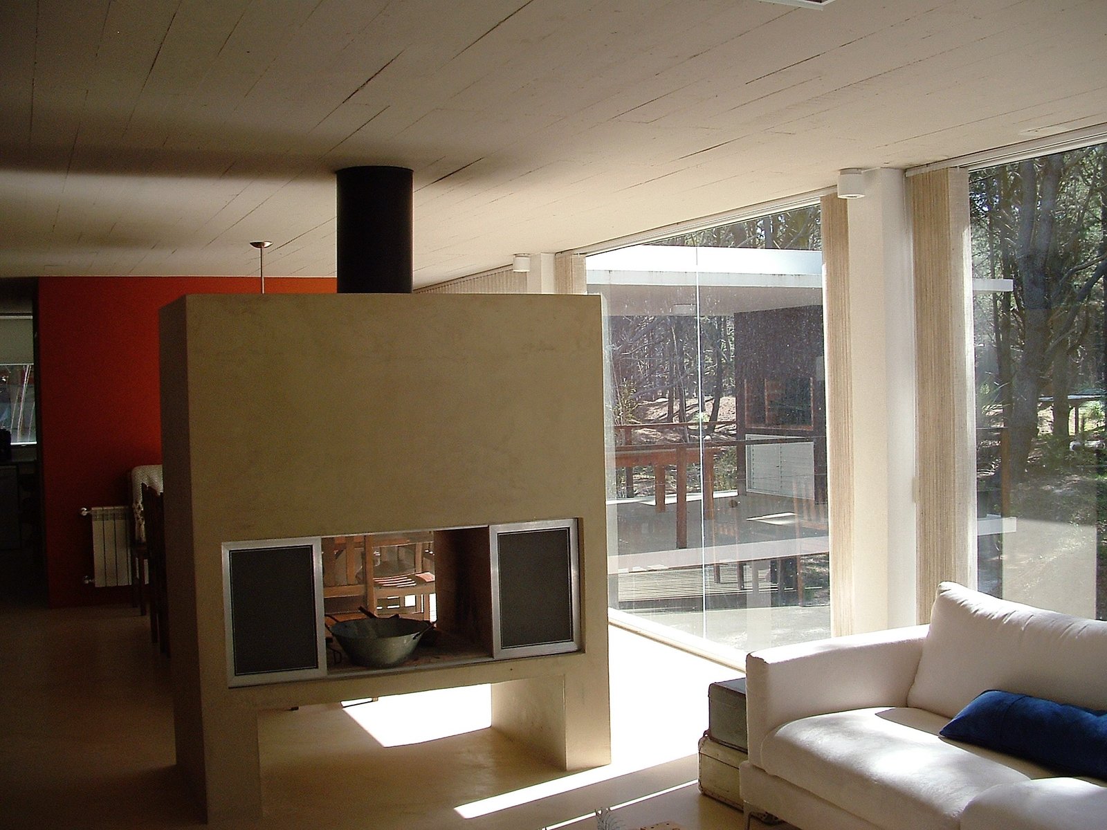 Sala de estar moderna com lareira central e painéis de madeira — projeto villa del puente, por GJF estudio, em Costa del Este