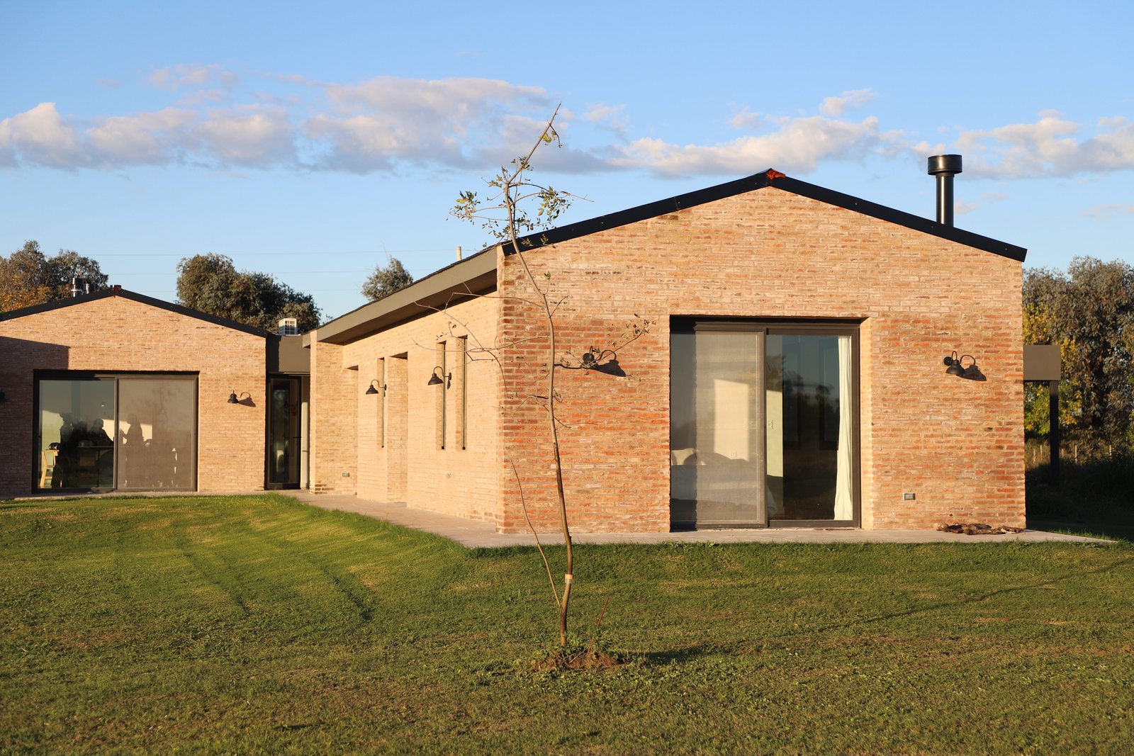 Casa moderna de ladrillo expuesto con amplios ventanales en entorno rural — proyecto Casa Areco, por R+B arquitectos, en San Antonio de Areco