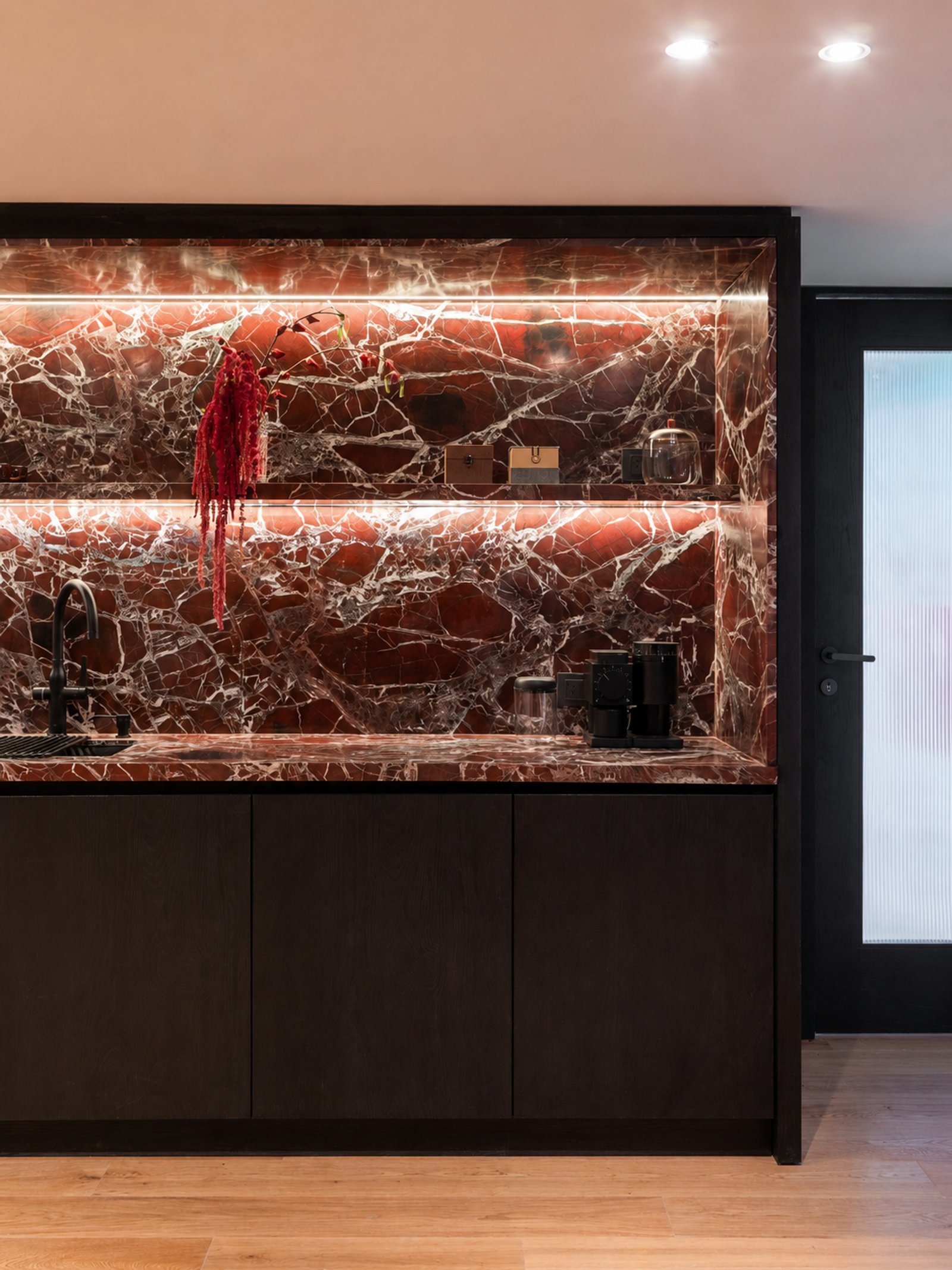 Cocina moderna con mármol rojo, iluminación integrada y muebles oscuros — proyecto Vidal, por Estudio Losa, en Belgrano
