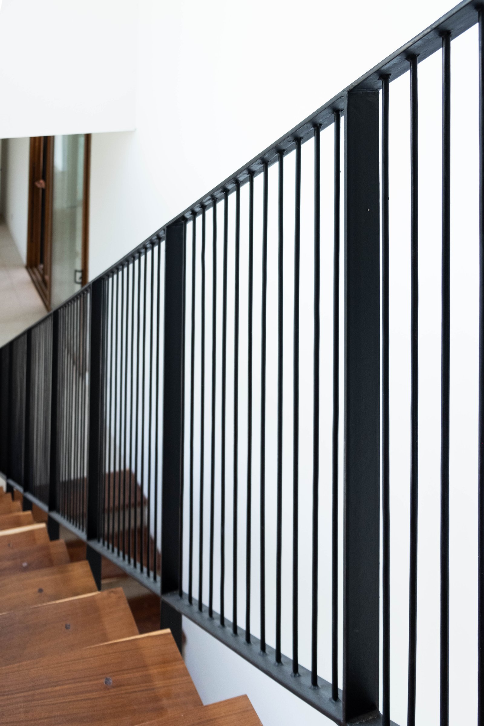 Escalera moderna con baranda negra y escalones de madera — proyecto CASA GOLF, por SEDE Arq., en Av. Pereda S/N