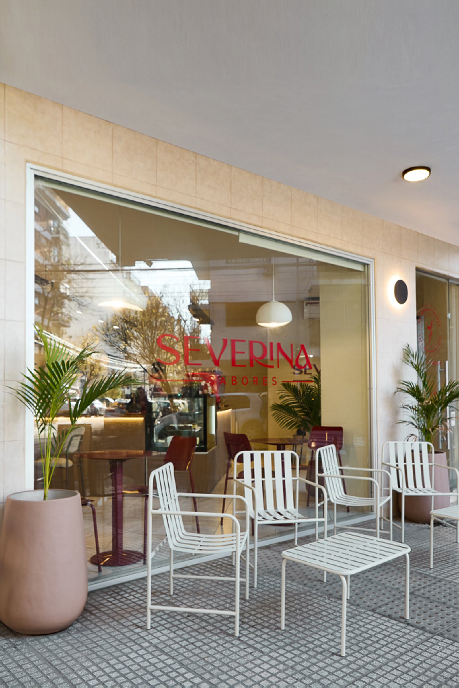 Fachada de cafetería con mesas y sillas de metal blancas — proyecto Severina, por Estudio Plats, en Acoyte 1396