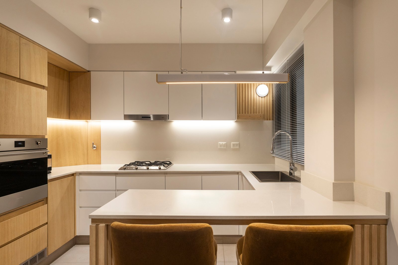 Cozinha moderna com armários de madeira clara e iluminação indireta — projeto BARRACAS, por La Nave Arq., em Barracas