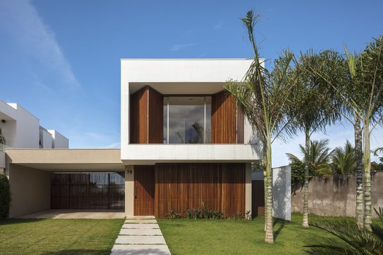 Casa moderna de dos plantas con fachada blanca y madera, jardín verde al frente — proyecto Casa Olhos D'água, por Aguirre Arquitetura