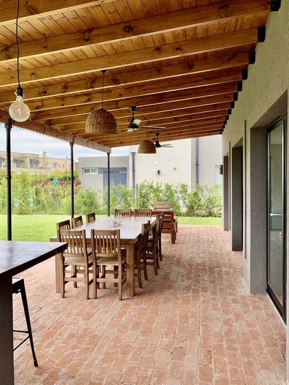 Galería rústica con techo de madera y piso de ladrillo, con comedor exterior — proyecto La Comarca , por Marconi Silva Arquitectos, en La Comarca