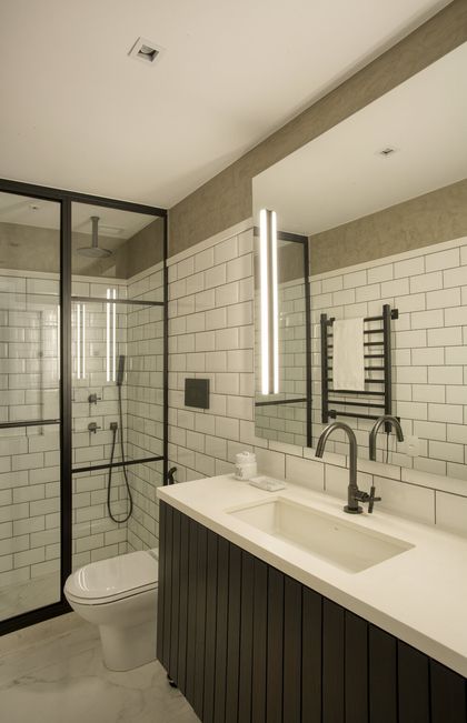 Baño moderno con mesada de mármol, espejo iluminado y ducha vidriada — proyecto JG House, por Studio Ro-ca