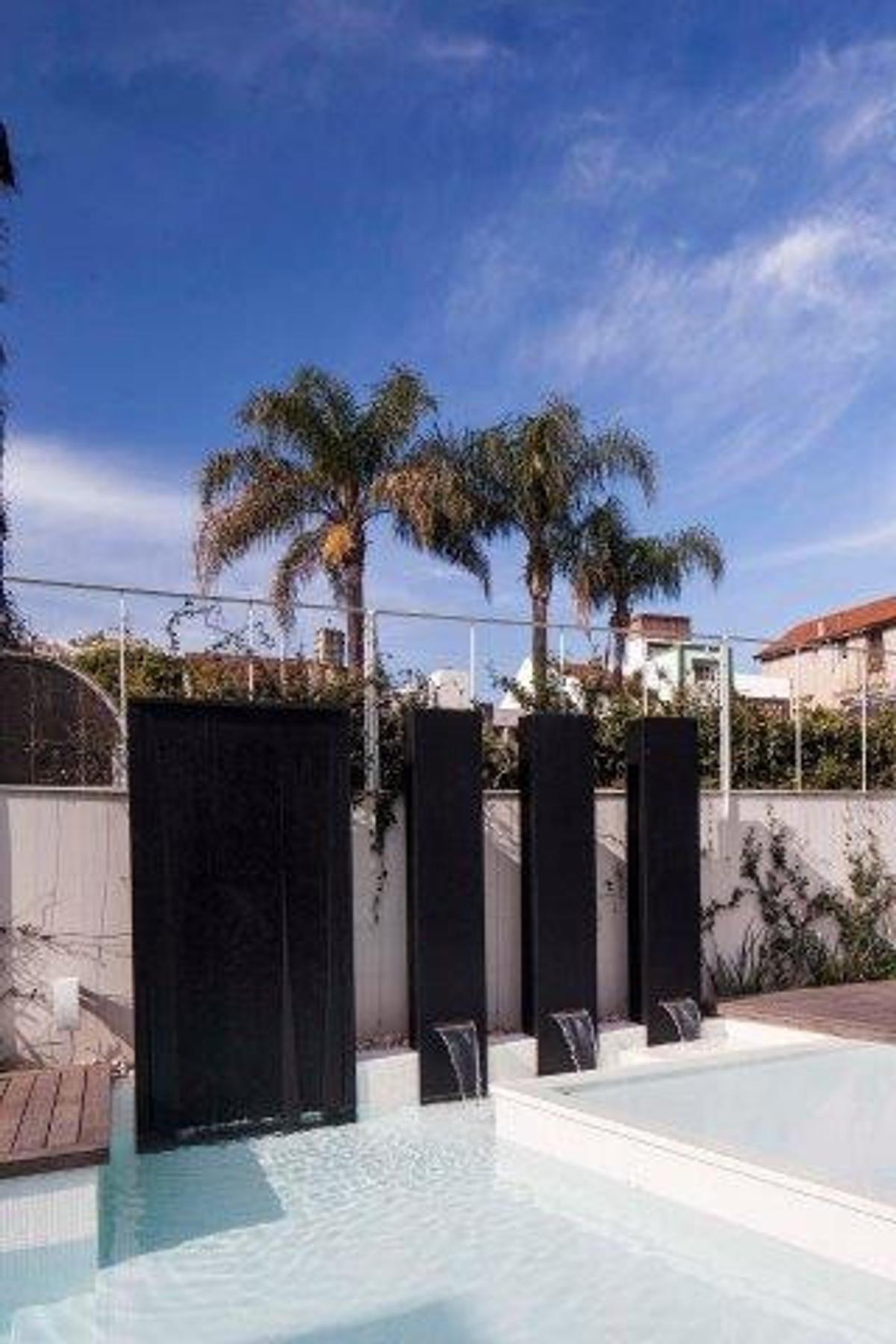 área de piscina moderna com cachoeiras e palmeiras — projeto Casa PMorán, por Vanguarda Arquitectos, em CABA