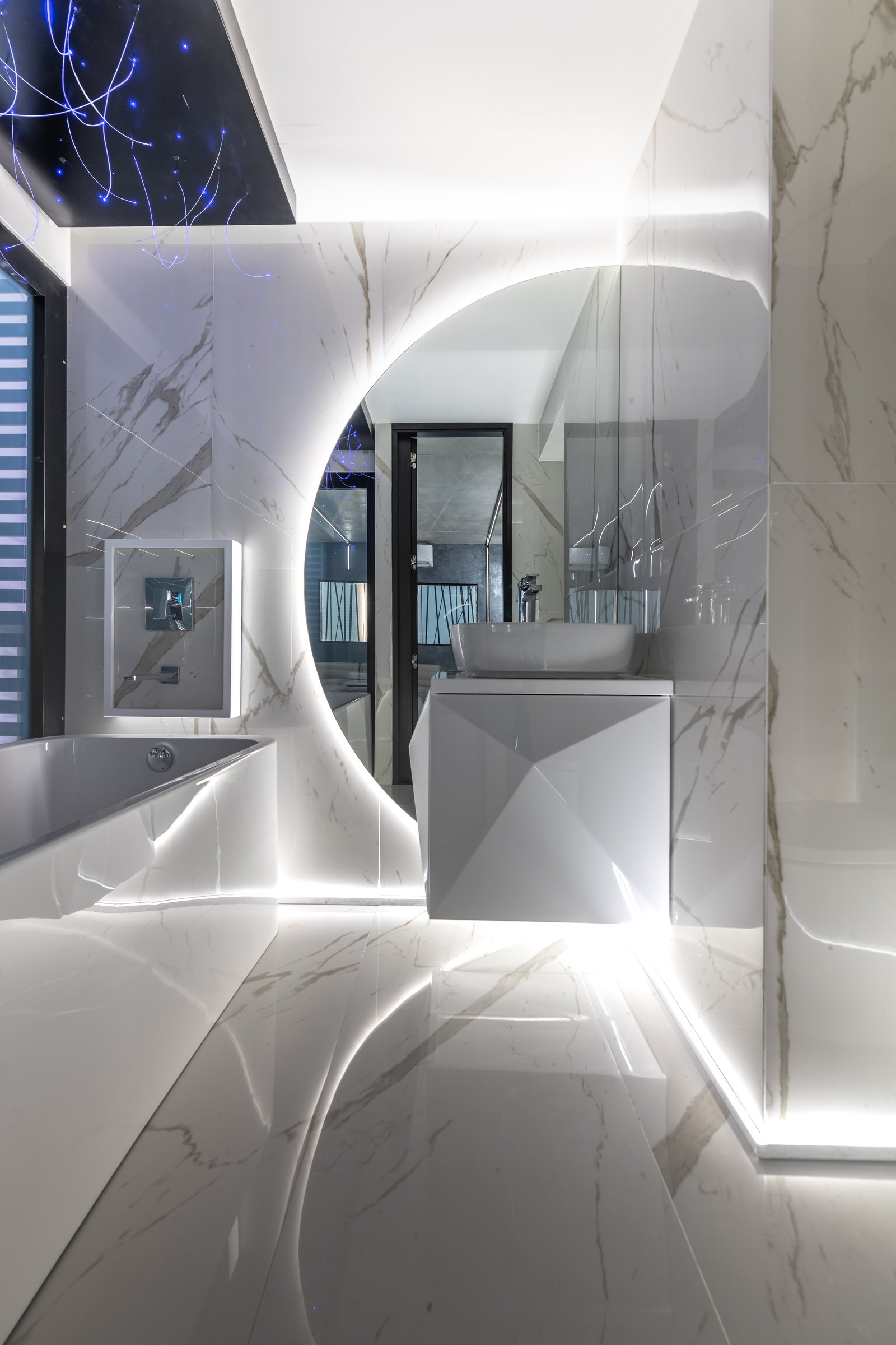 baño moderno con espejo circular retroiluminado y acabados de mármol — proyecto Marmoles, por Vite Porcellanato