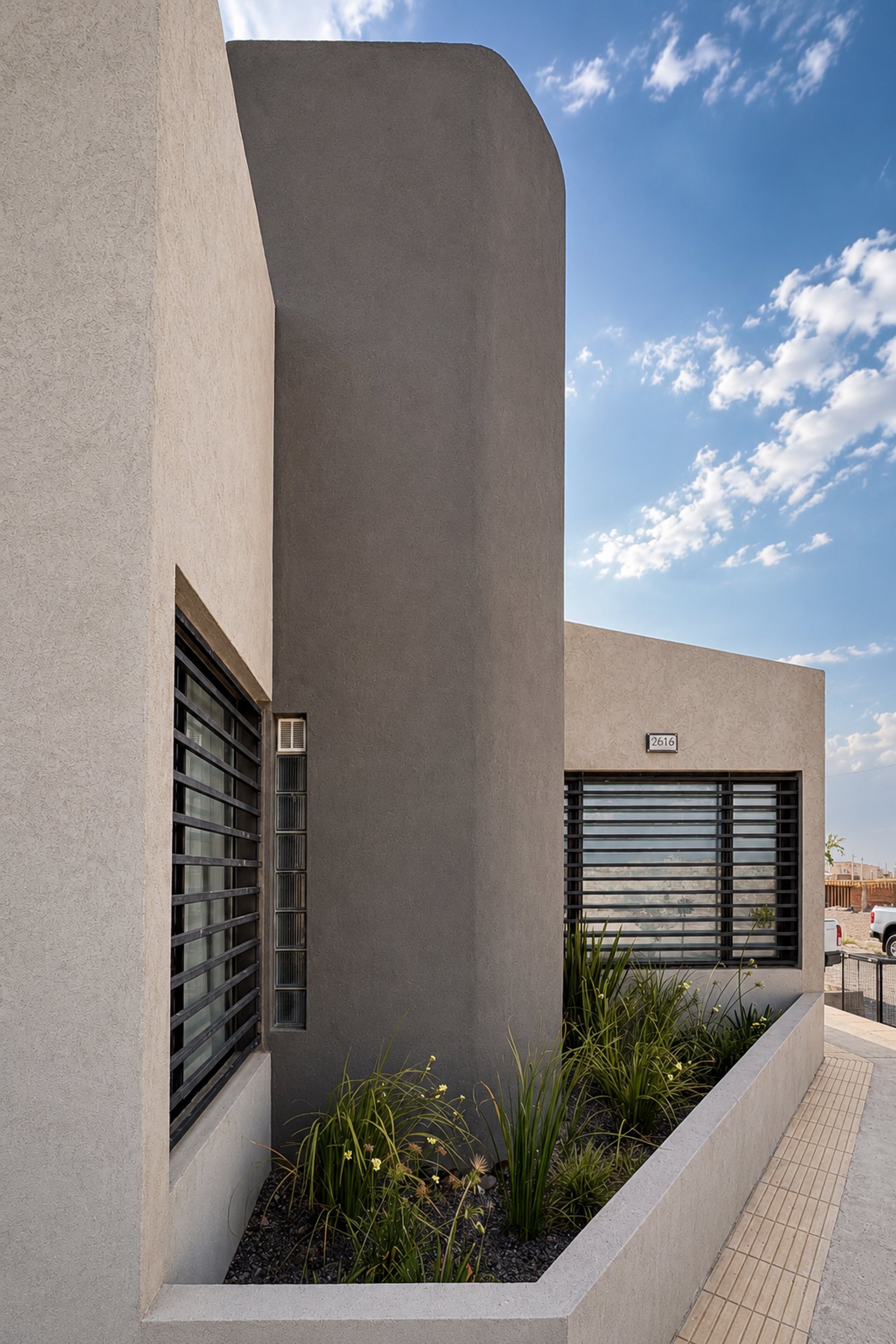 Fachada moderna con muro curvo y contrastes de texturas — proyecto Casa AJ, por Pedro Vilchez, en Neuquén