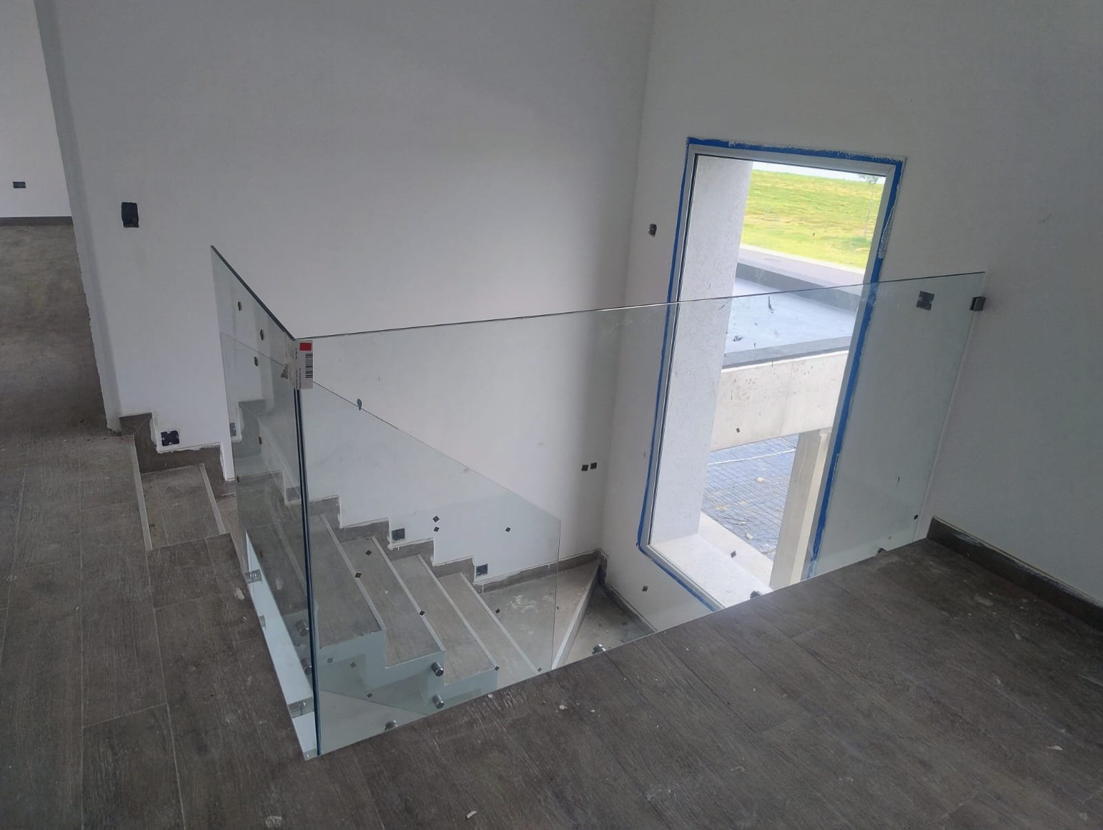 escalera moderna en construcción con barandas de vidrio — proyecto Baranda templada 10mm con botones acero 38mm, por Cristalcenter, en Belén de Escobar