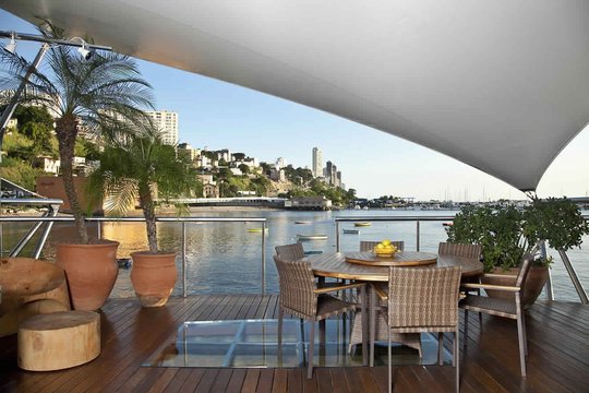 Terraza con vista al río, comedor de madera y pergola moderna — proyecto Varandas, por Xico Diniz