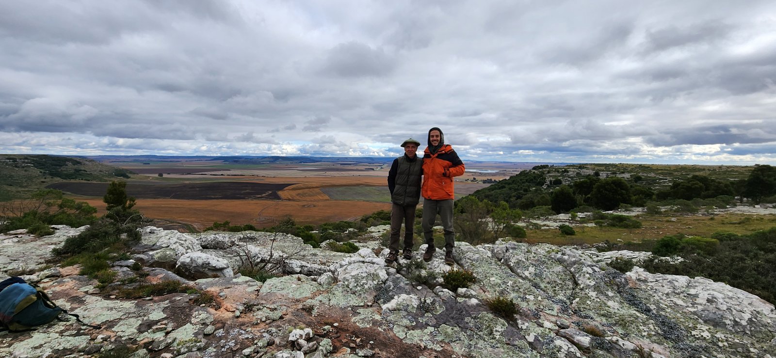 dos personas en roca con paisaje árido — proyecto Reserva Naural Paititi, por Estudio Rifahi, en Sierra de los Padres