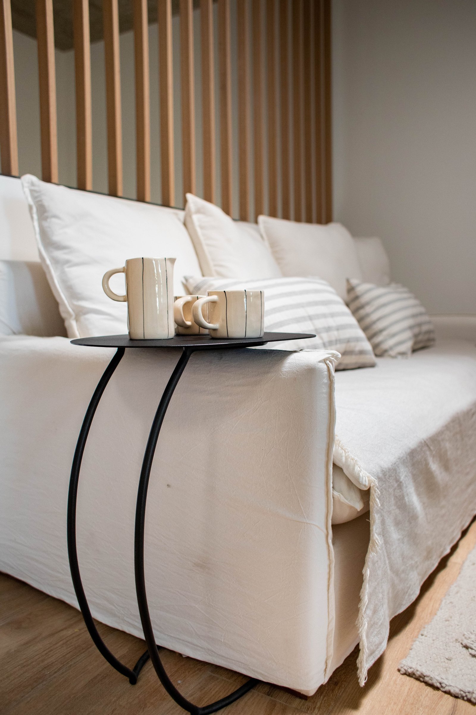 Living con sofá blanco, mesa negra y pared de listones de madera — proyecto Ovejitas, por LACROZE DESIGN STUDIO, en San Isidro