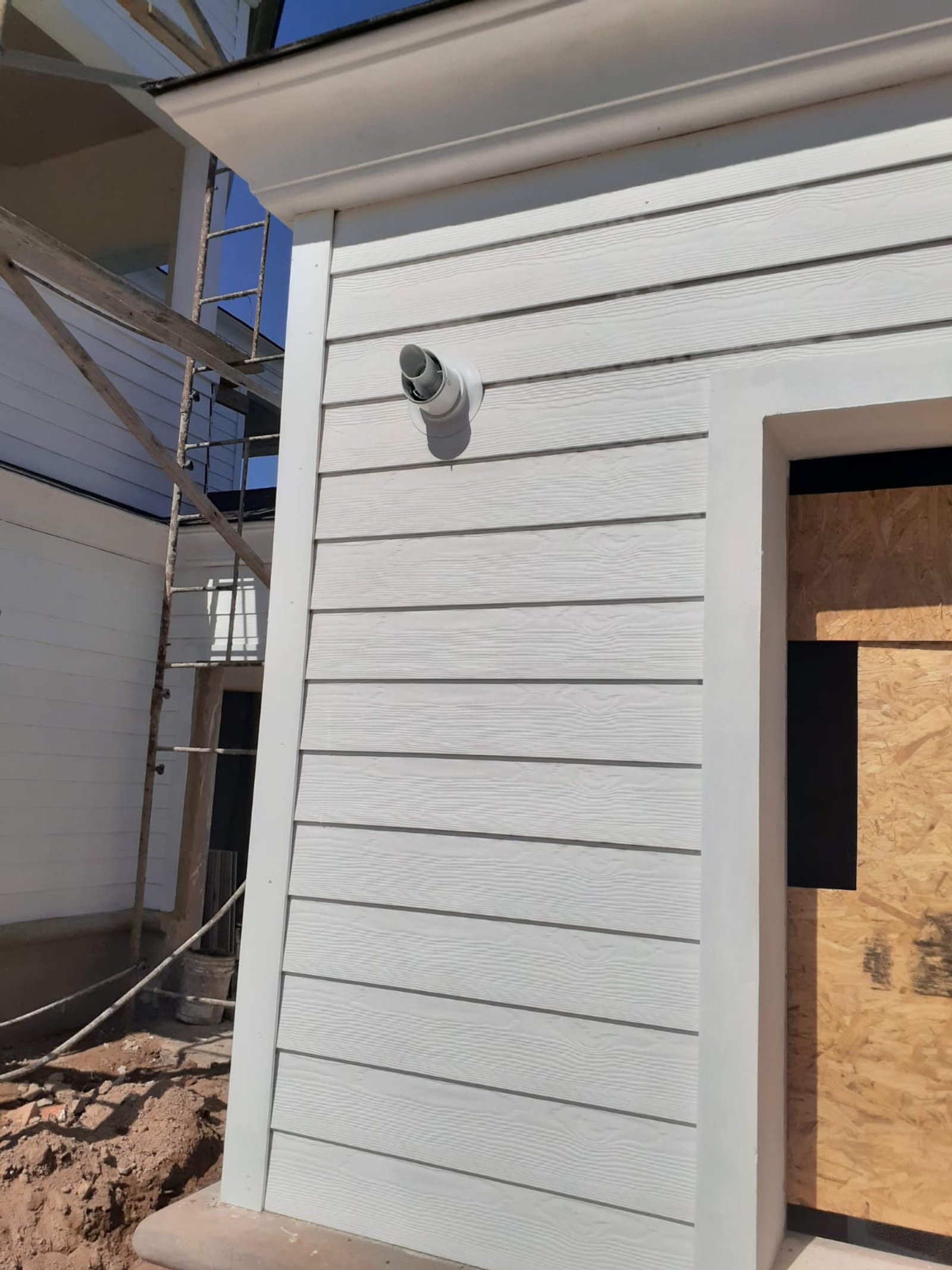 fachada residencial en construcción, revestimiento blanco — proyecto Piso Radiante en barrio Las Vizcachas, por Crisol Clima SRL, en PX3C+9G