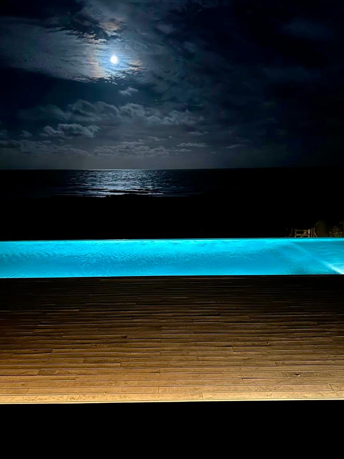 Piscina infinita iluminada sob a lua com deck de madeira — projeto CASA sobre el MAR, por Guerrero Arquitectos, em Pinamar