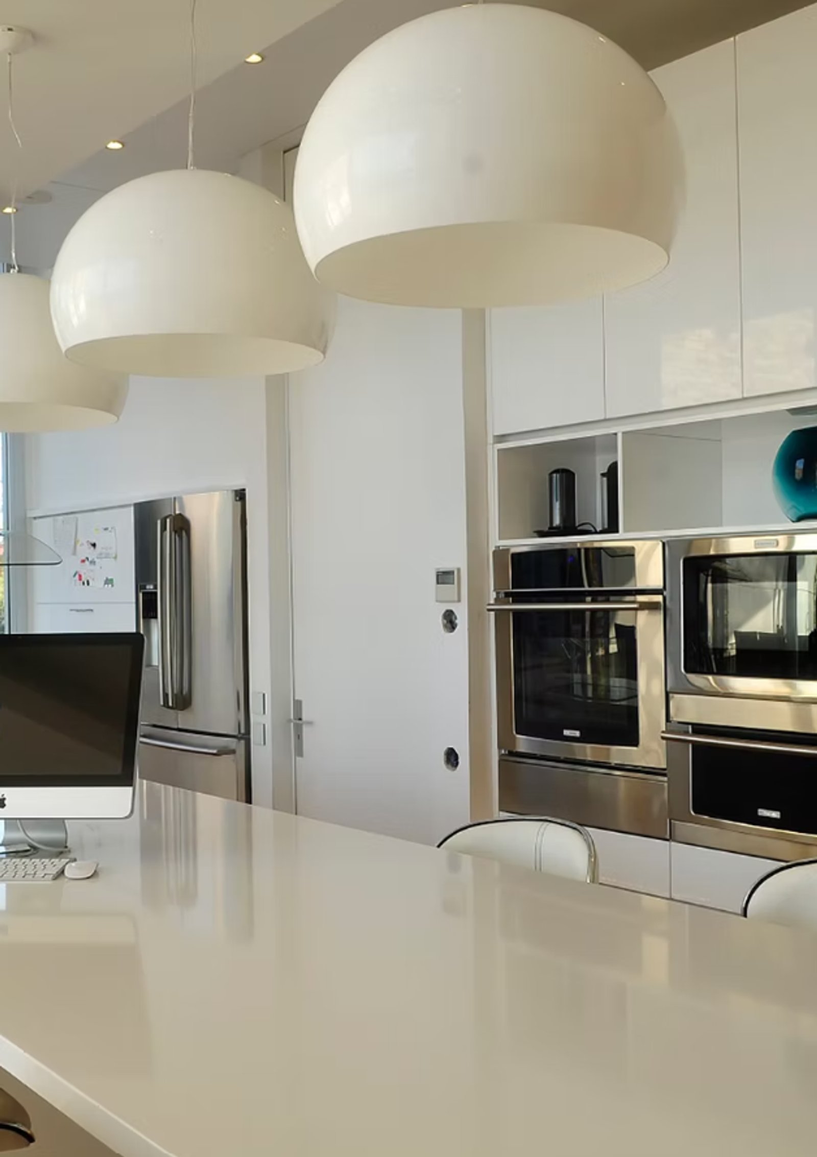 Cozinha moderna com ilha grande, eletrodomésticos embutidos e luminárias pendentes — projeto Casa Cinta, por Barrionuevo Arquitects, em B2814 Los Cardales