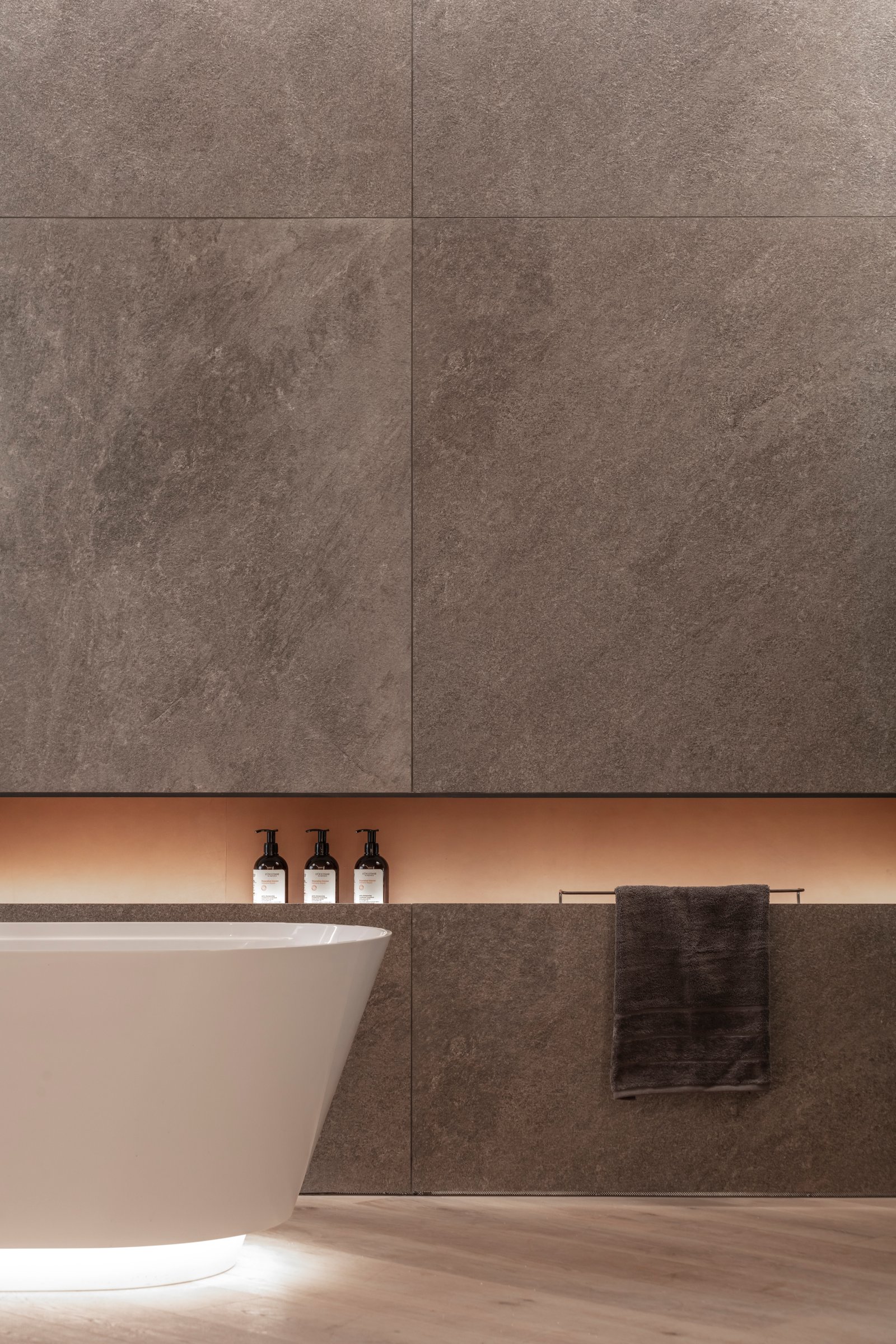 Baño moderno con bañera exenta blanca, iluminación indirecta y revestimiento de piedra — proyecto Casa Foa 2024 | Ritual de bienestar | Wellness ritual | Lucia Quinteros, por Ren S
