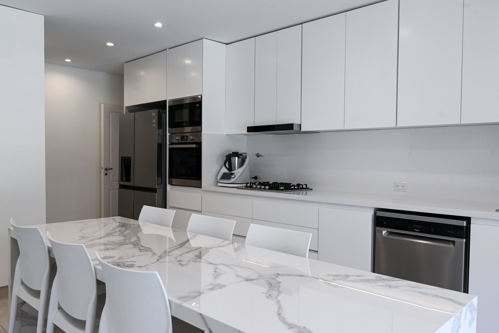 Cocina moderna abierta con isla y revestimientos de mármol blanco — proyecto SANTA BÁRBARA, por ESTUDIO TEZ, en Corredor Bancalari - Benavidez 3901