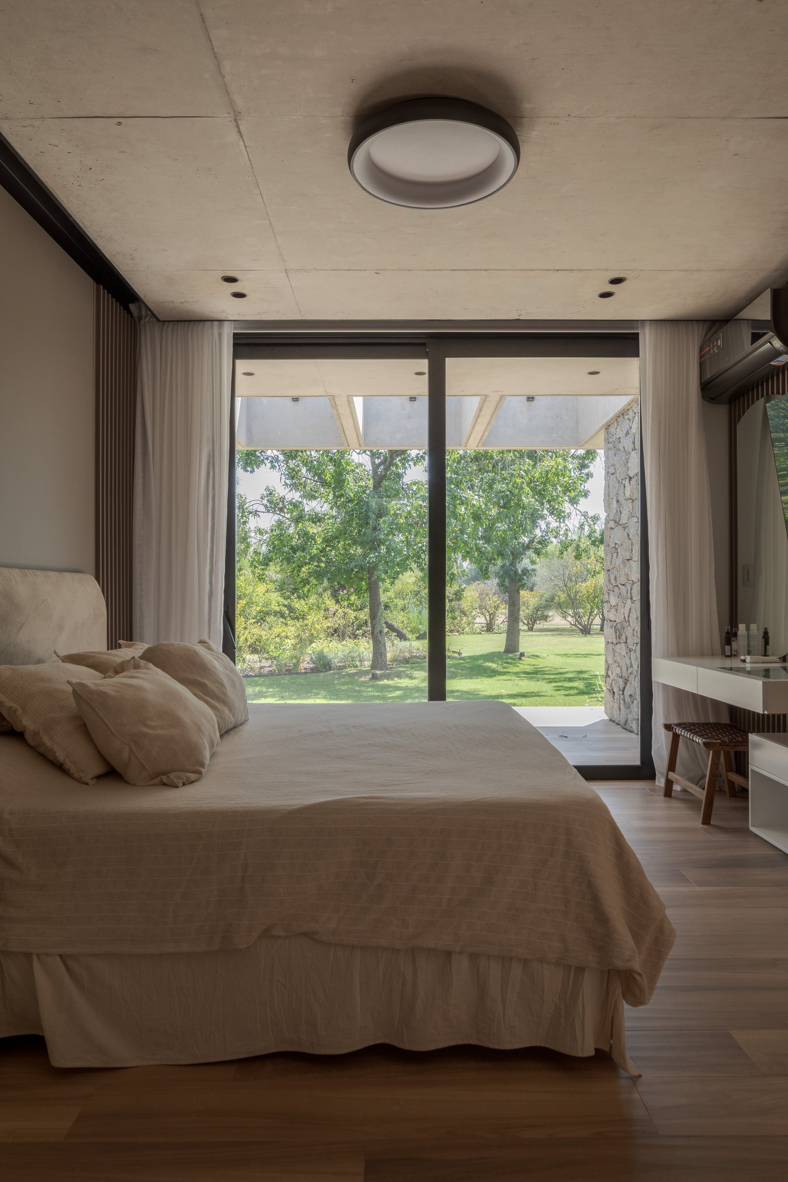 Dormitorio moderno con vistas al jardín y techo de hormigón — proyecto Casa PLANALTO, por Grupo CRBN, en Av. Pres. Perón 10298