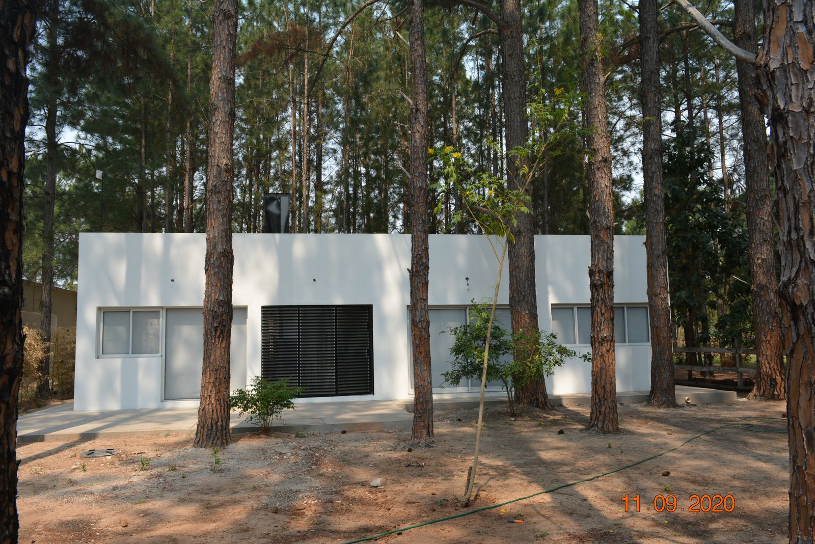 Fachada de casa moderna blanca en bosque con árboles altos — proyecto Casa en el Bosque, por Arquitecto Gustavo Maidana, en Santa Ana de los Guácaras