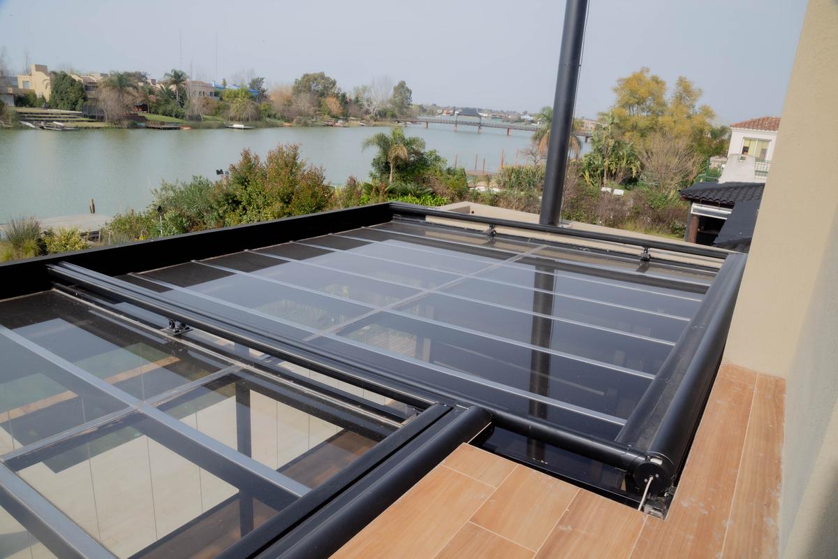 terraço com teto retrátil de vidro sobre lago — projeto TOLDER - TOLDOS, por Argentina en Obra 2024, em Rincón de Milberg