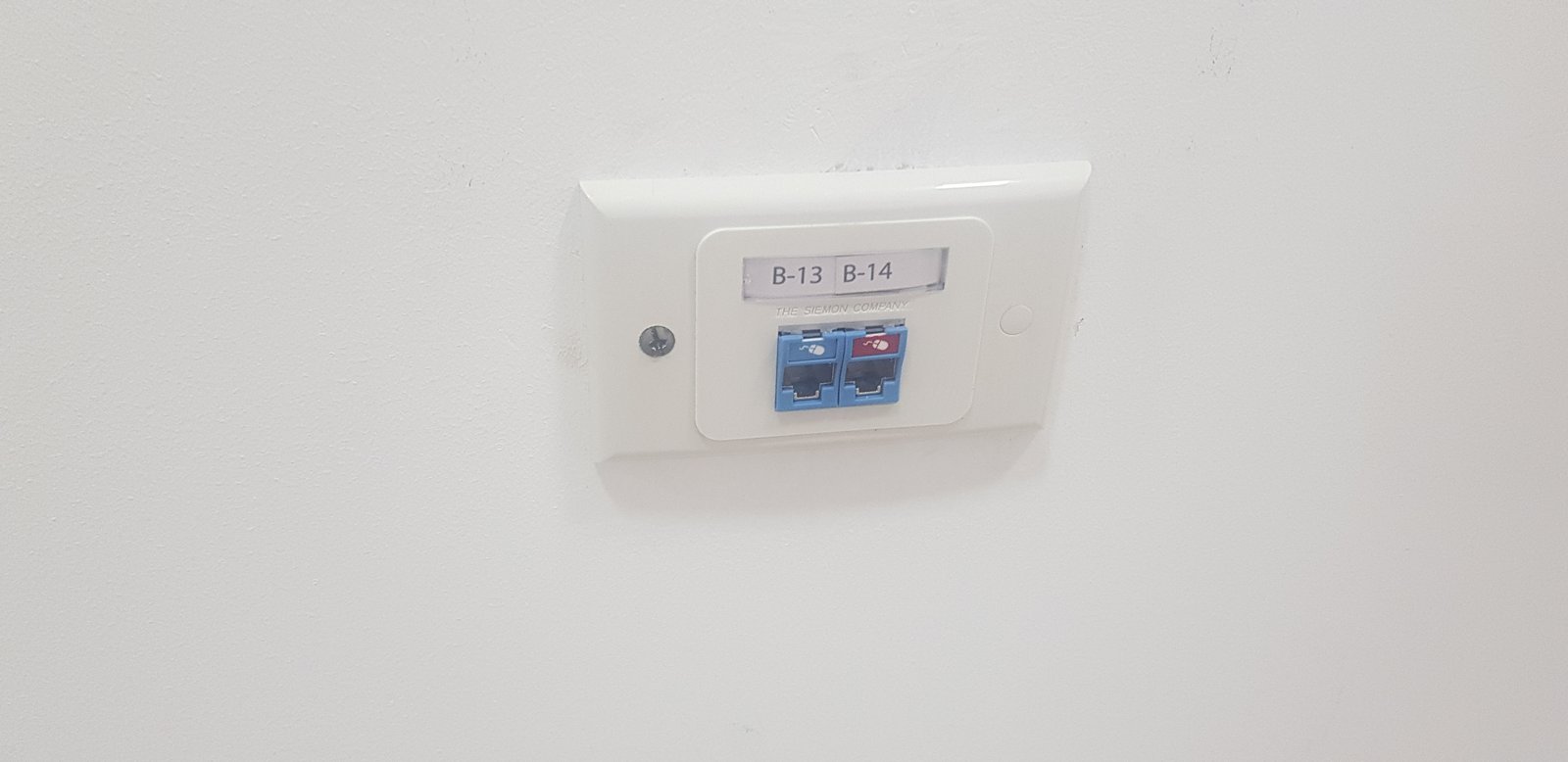 Caja eléctrica blanca montada en pared con puertos y etiqueta — proyecto Montajes eléctricos en oficinas Comerciales , por Mantenimientos Comerciales Leon , en Buenos Aires