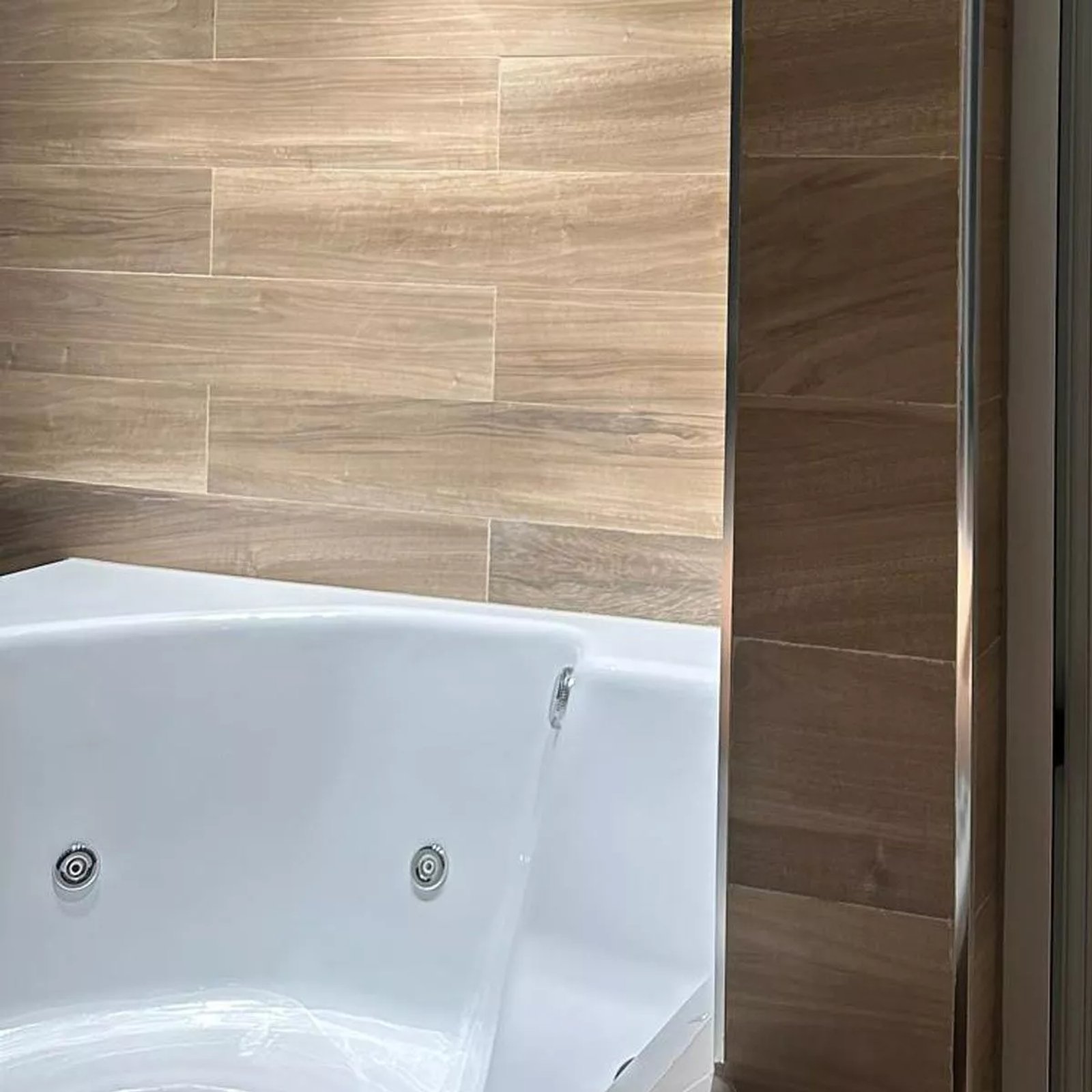baño moderno con bañera blanca y detalles en madera — proyecto Experiencia única en Del Bono Park, por ATRIM GLOBAL, en San Juan