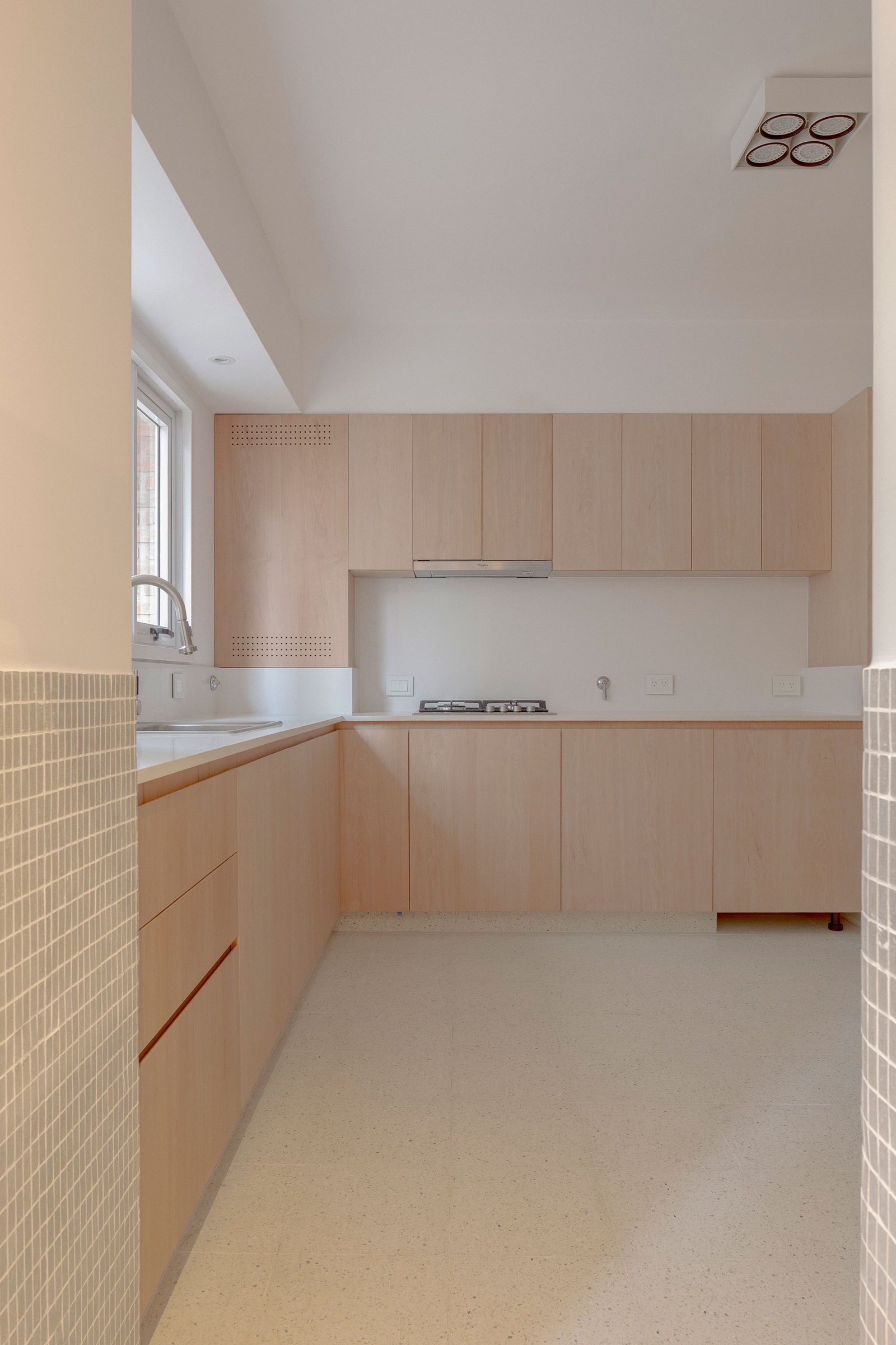 Cozinha escandinava minimalista com armários de madeira clara e bancadas brancas — projeto Reforma O'Higgins, por Estudio YME, em Belgrano