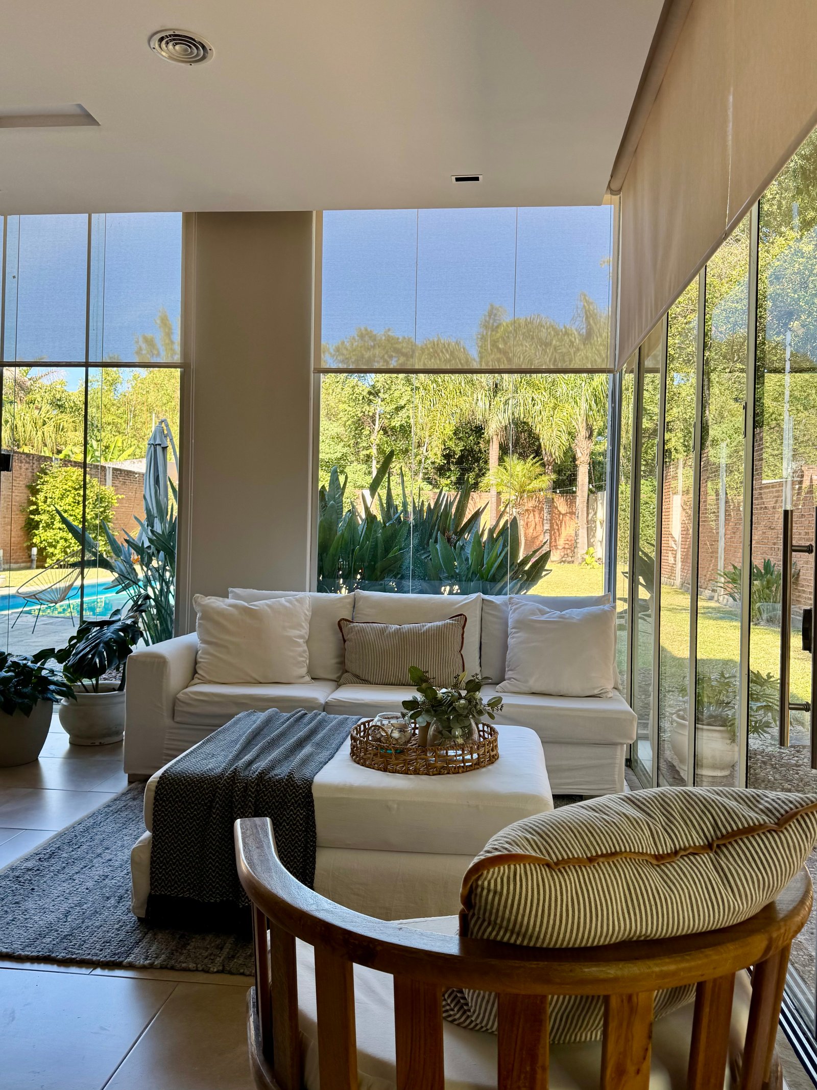 Sala de estar moderna com vista para o jardim e sofá branco — projeto Casa LAS HERAS quincho, por María Isabel Wetzel, em Ciudad de Corrientes