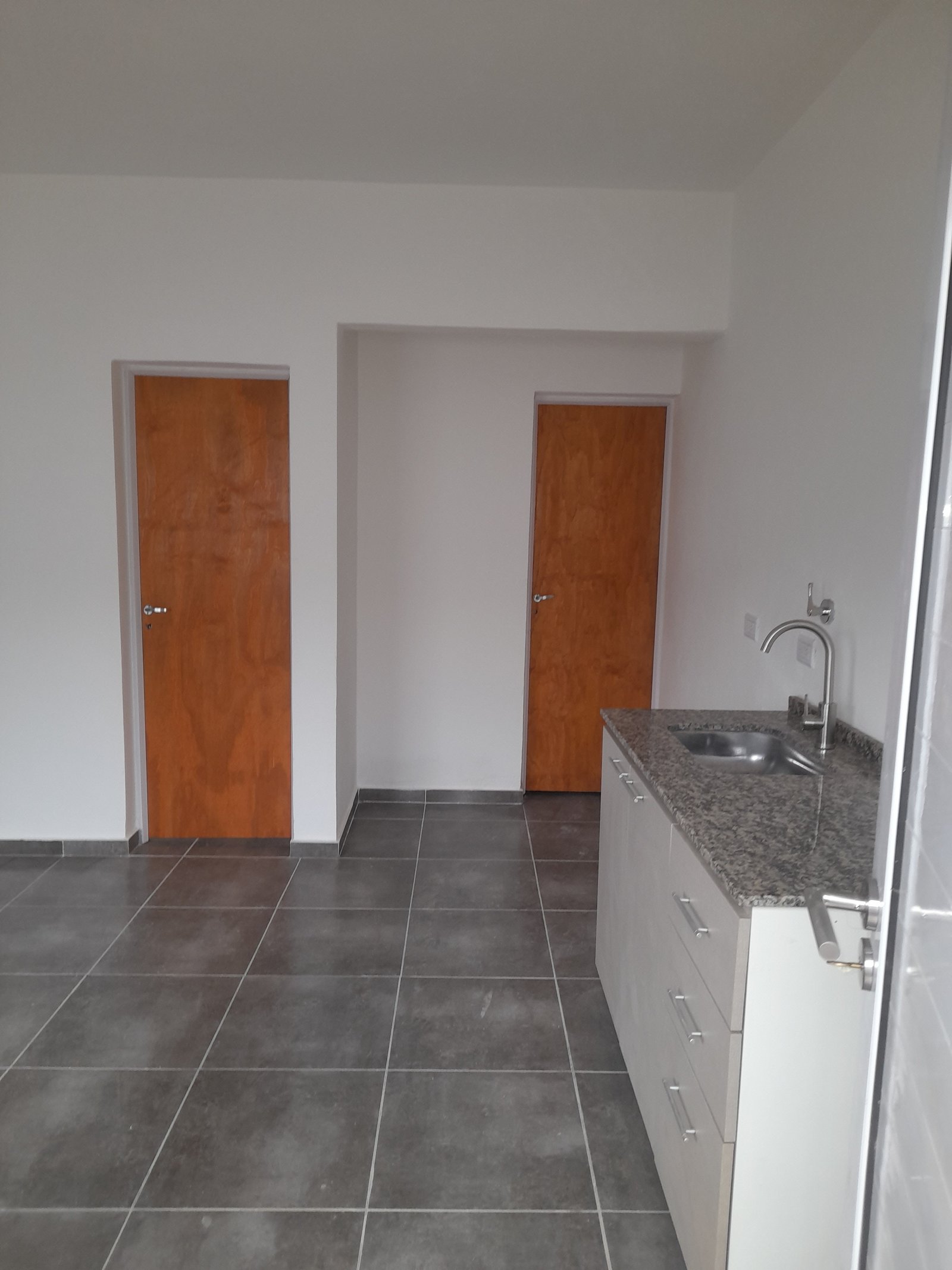 Cocina minimalista con puertas de madera y muebles blancos — proyecto Departamentos, por CN Construcciones, en Alta Gracia