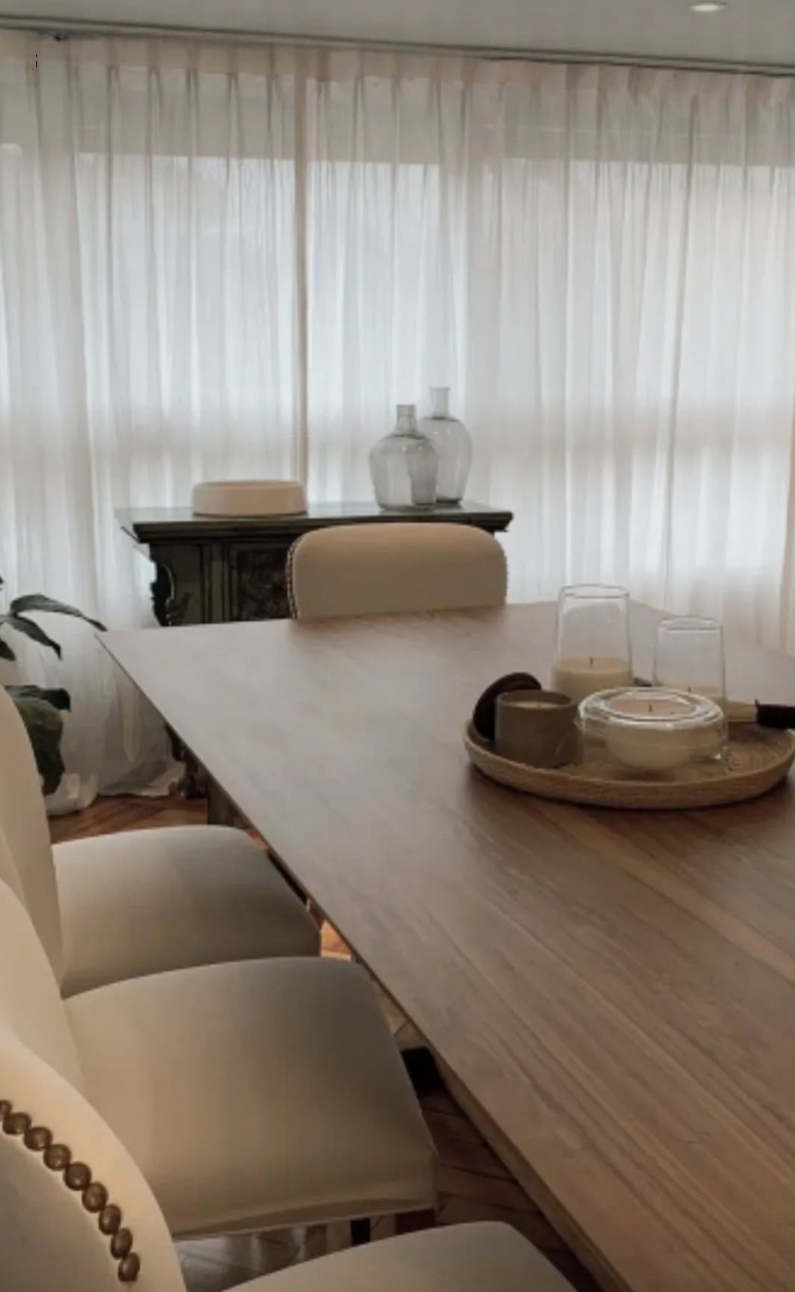 Comedor moderno con mesa de madera, sillas beige y cortinas blancas — proyecto Nuñez, por Claraboia , en Núñez