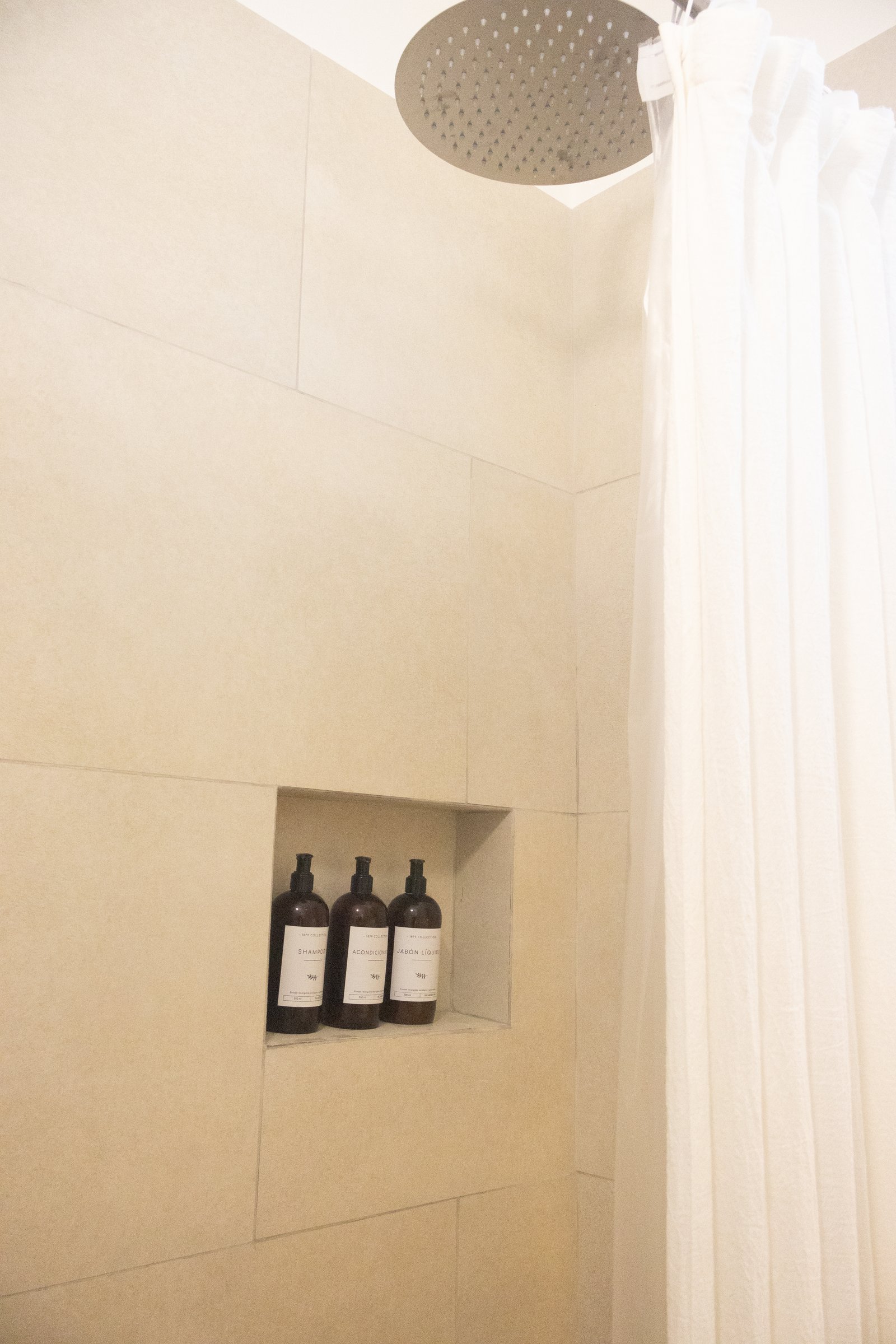 banheiro com azulejos de pedra bege e dispensadores em nicho — projeto Cabrera, por Estudio BDM, em Cdad. Autónoma de Buenos Aires
